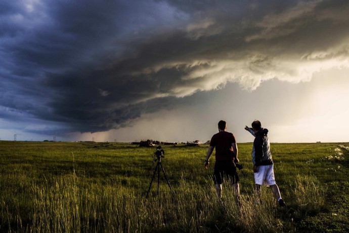 Two men enjoy a storm in the prairies at sunset