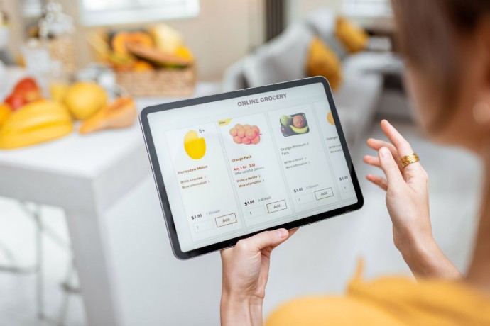Woman shopping food online using a digital tablet at the kitchen