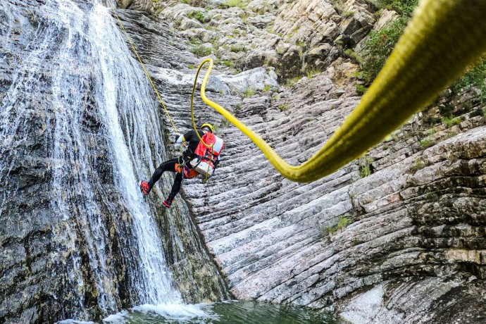 Canyoning adventurist going down the green rope