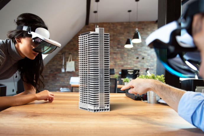 Two people working on virtual 3d building by using AR glasses.
