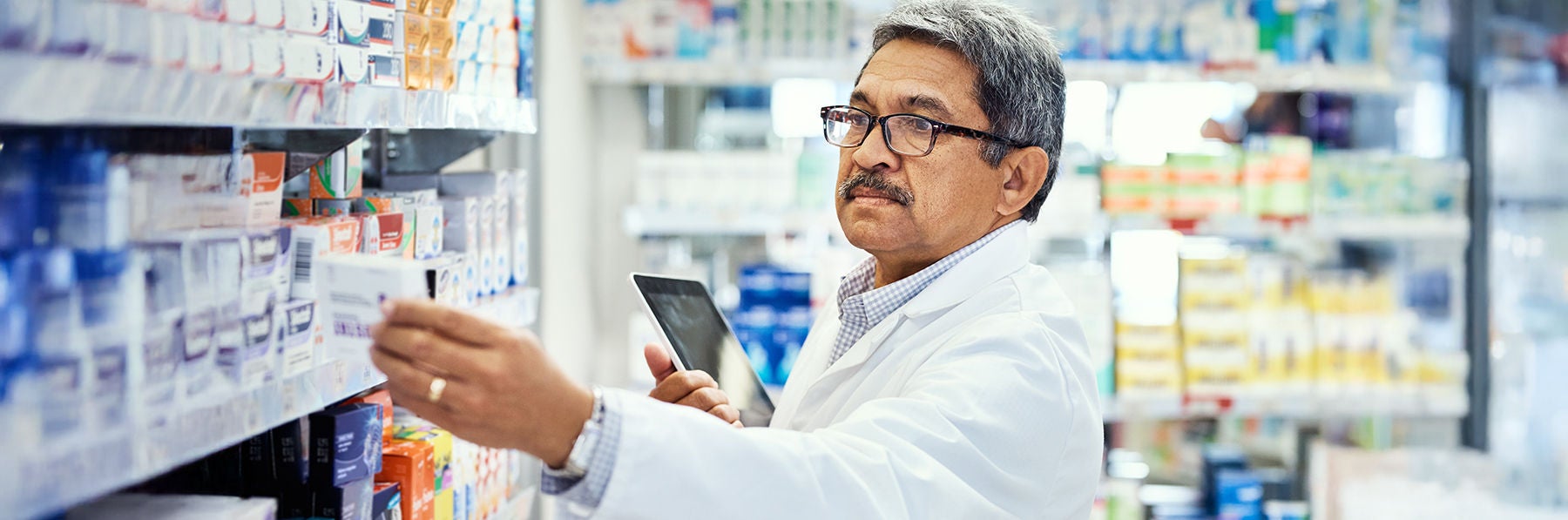 Pharmacist, tablet and pills in stock, inventory and medicine as chemist, drugstore and employee. Man, doctor and digital checklist in pharmacy, clinic or dispensary for prescription, help or advice.