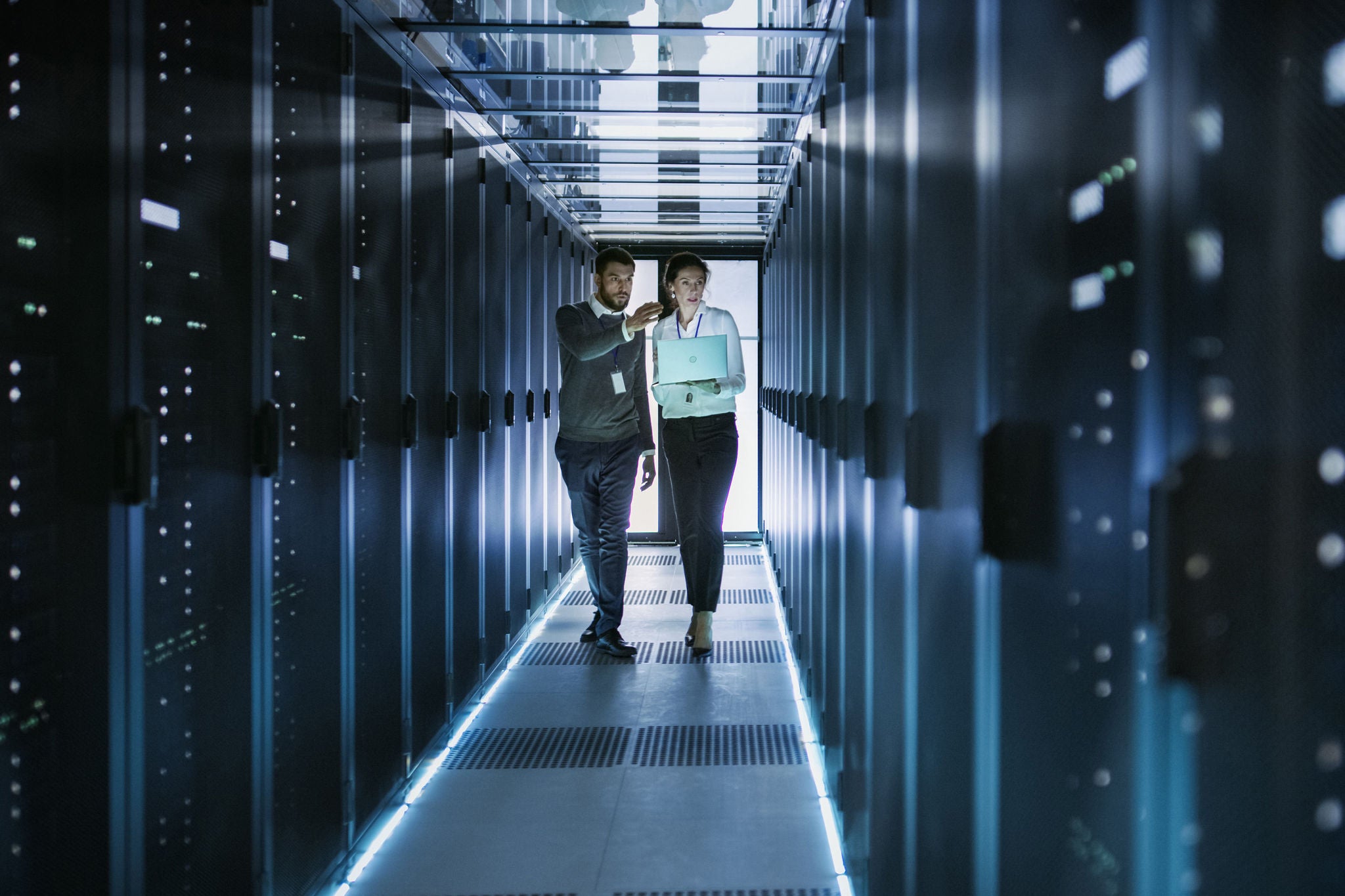 IT technician and engineer working in a data center full of rack servers