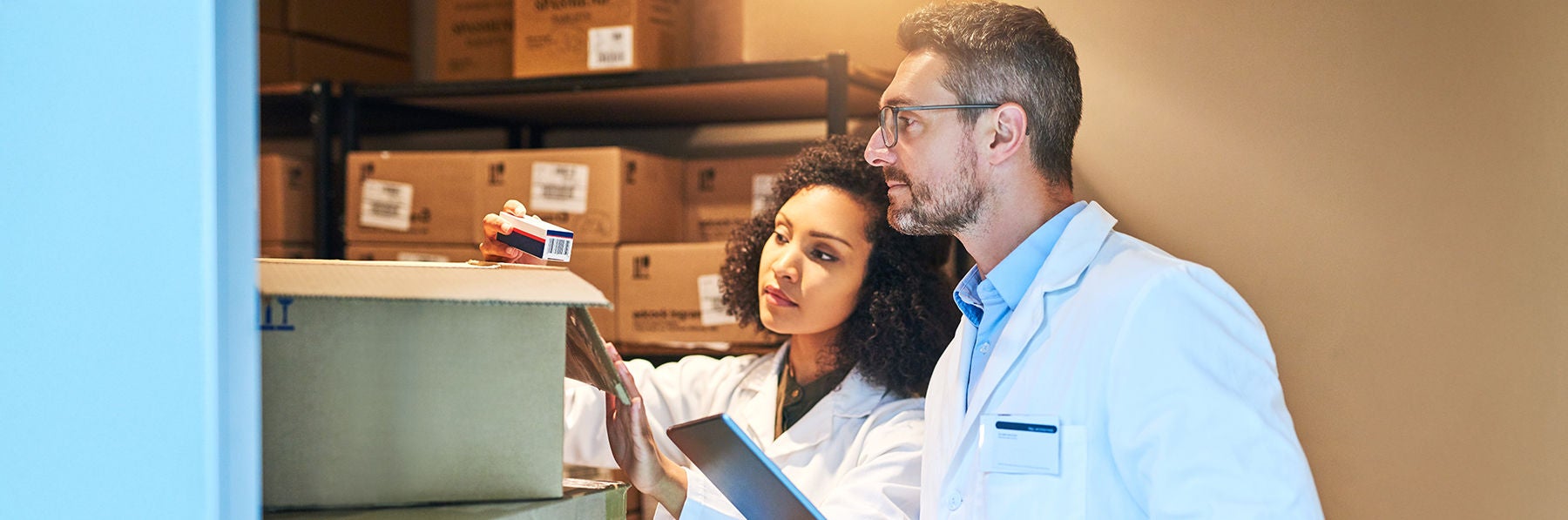 Tablet, box and pharmacy with people and inventory for shipping, cargo or medical supplies. Digital, checklist and delivery with man and woman in storage room for medicine, healthcare and drugs store.