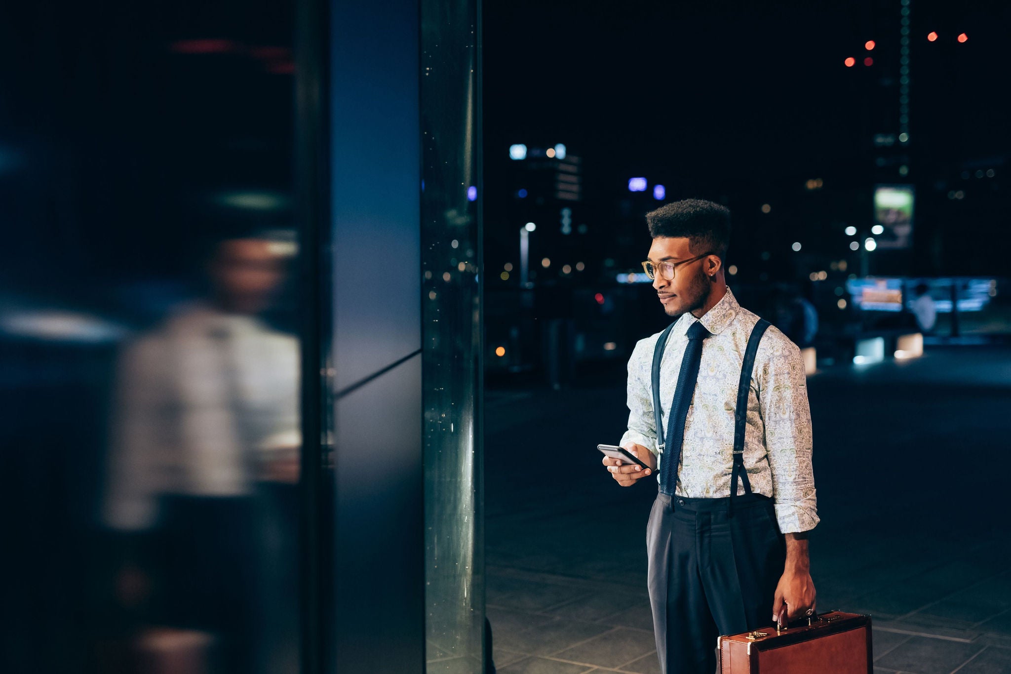 A businessman with phone and bag peers into building window