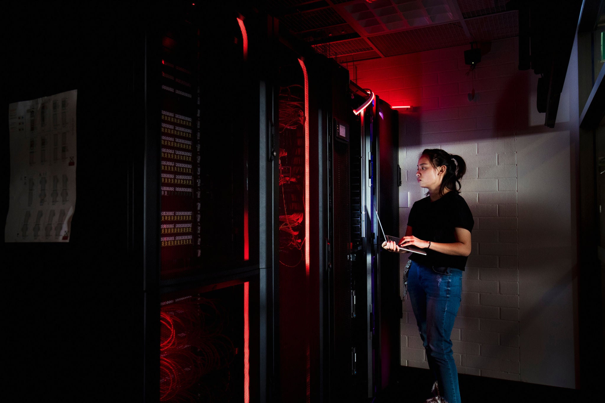 young Chinese woman in a server room with hi-tech supercomputers on display, LED lights are surrounding the equipment she is using