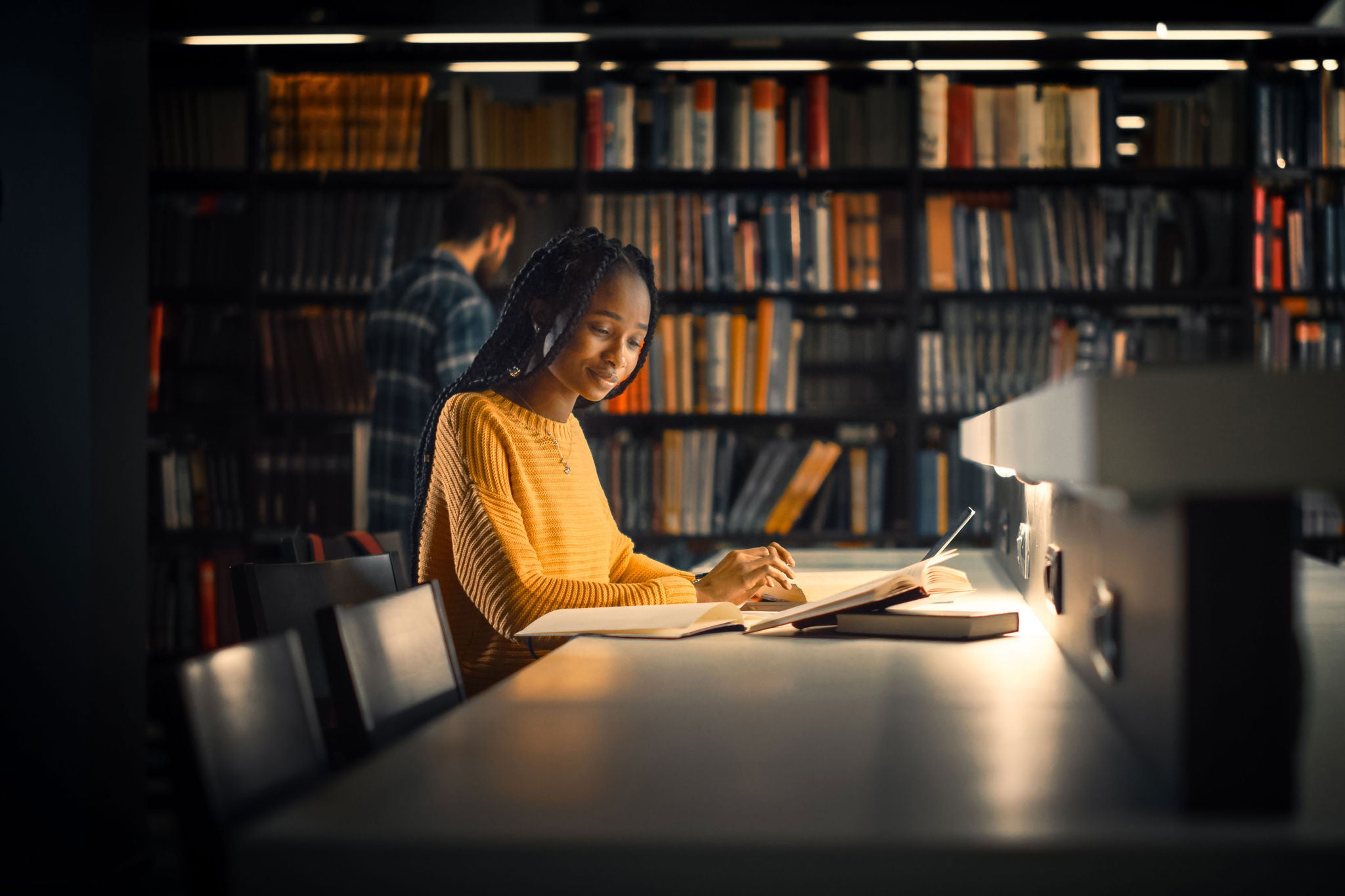 University Library: Gifted Black Girl uses Laptop, Writes Notes for the Paper, Essay, Study for Class Assignment. Students Learning, Studying for Exams College. Side View Portrait with Bookshelves