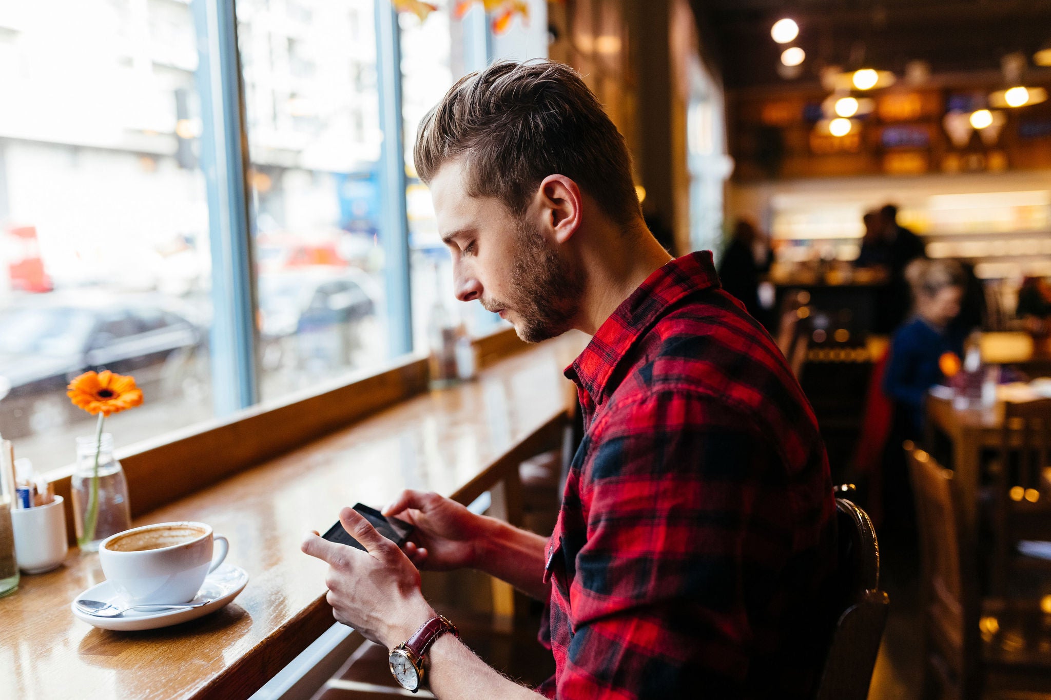 Man in a coffee shop looking at cell phone