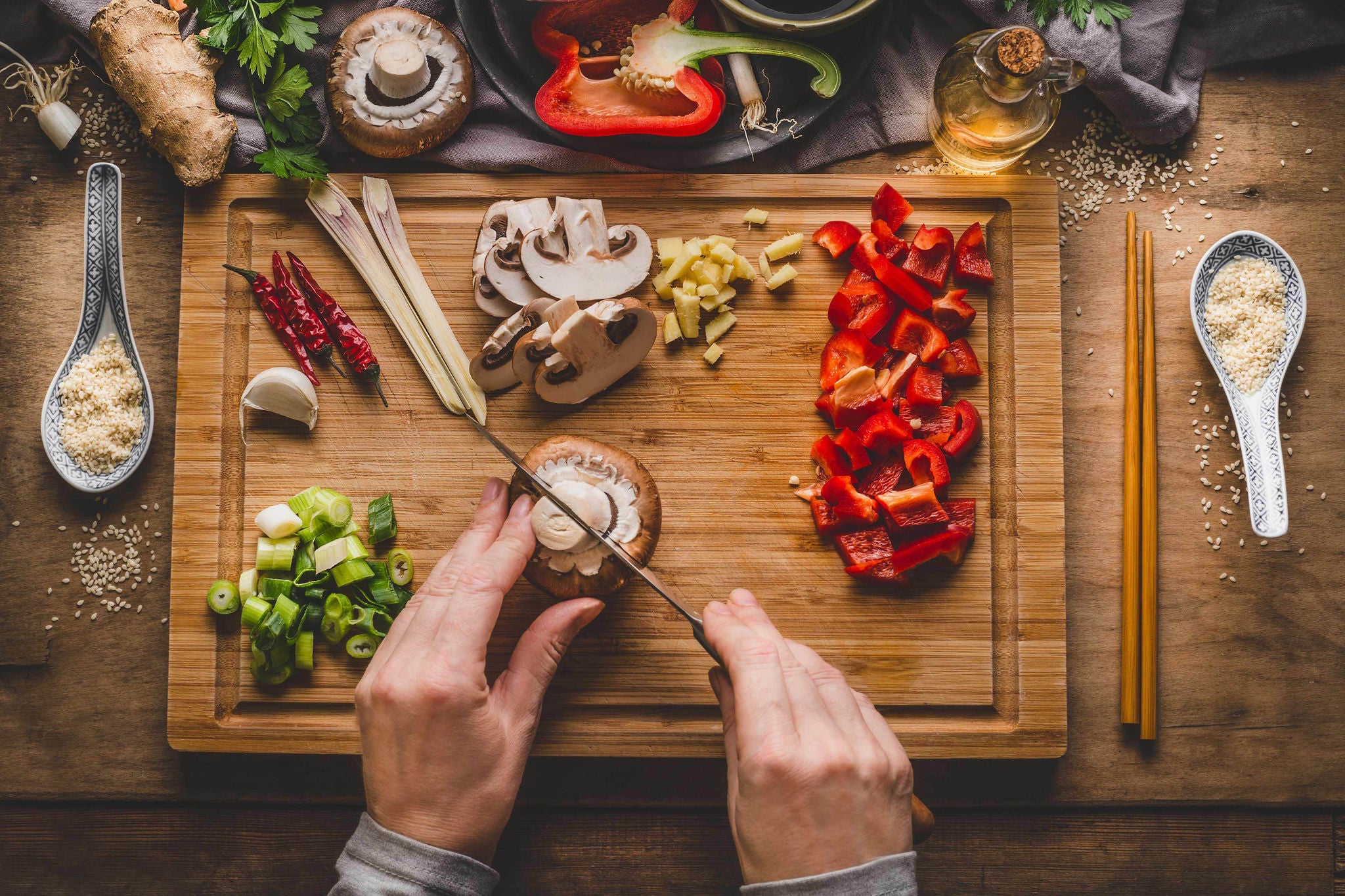 Vegetarian stir fry cooking preparation. Women female hands cut vegetables for stir fry on kitchen table background with ingredients, top view. Asian food , Chinese or Thai cuisine concept