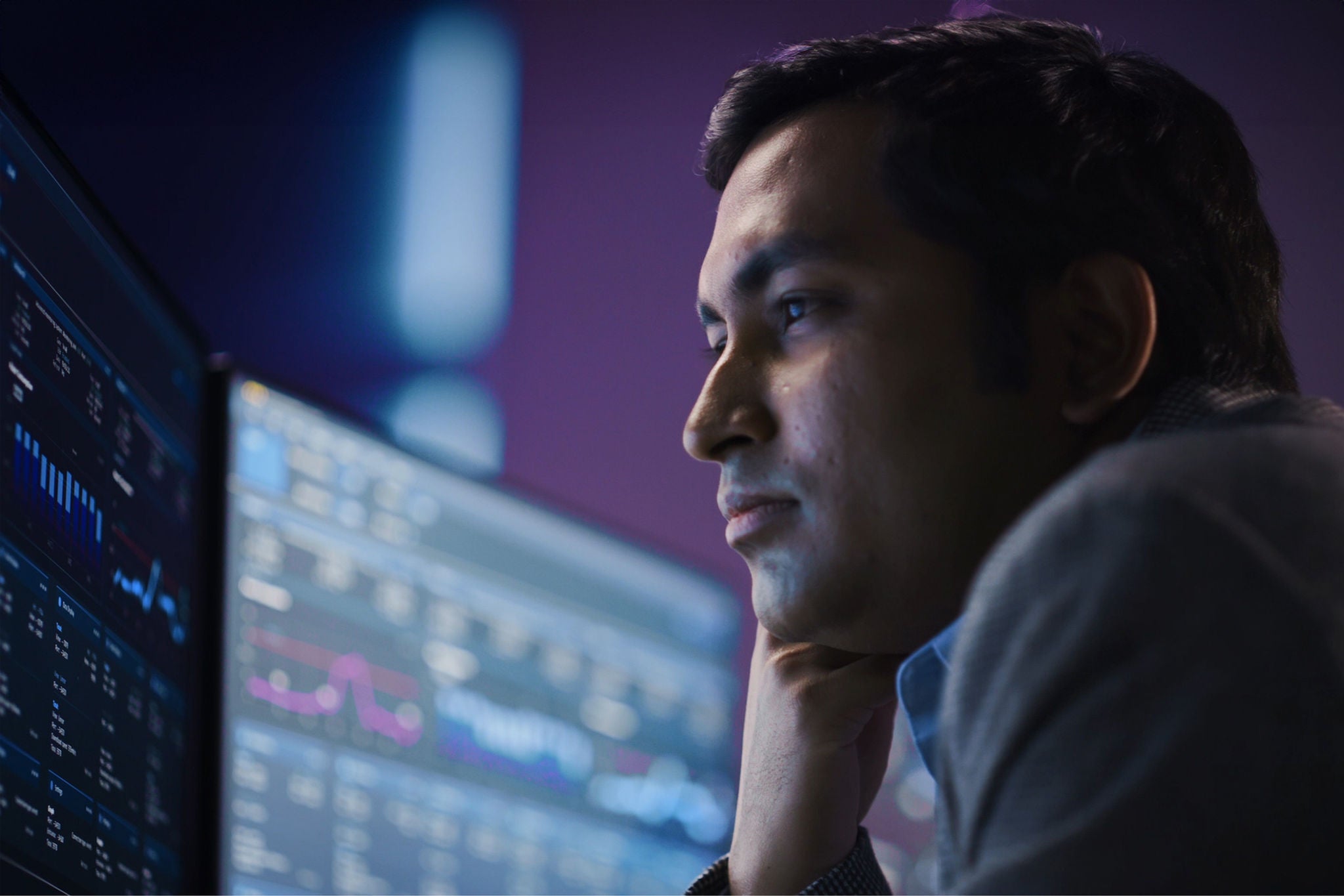 Confident Handsome Man Looks at Computer Monitor, Screen Showing Data, Infographics, Information, Statistics, Numbers. Businessman Working on Computer in the Office