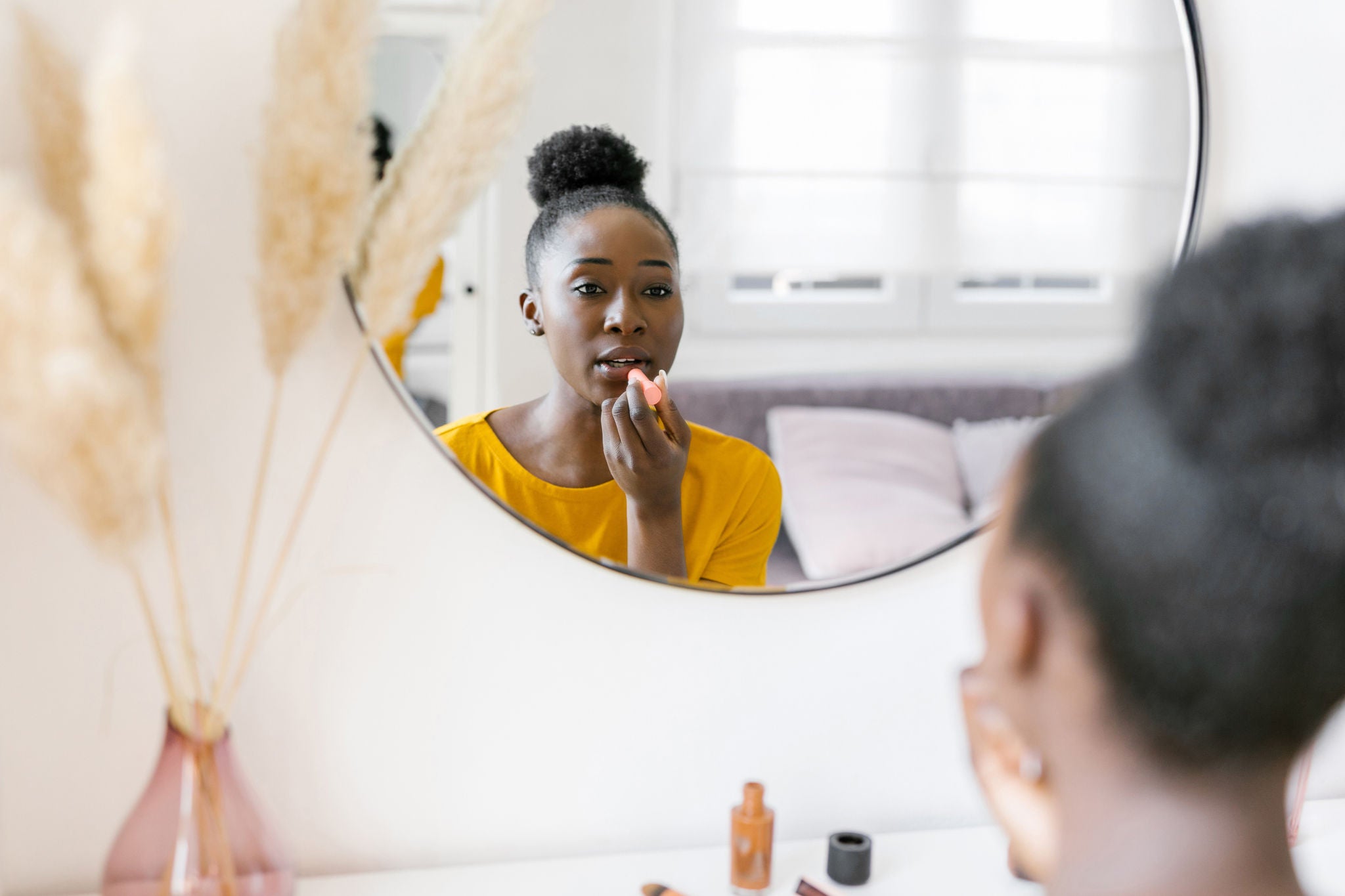 Beautiful young woman applying a lipstick