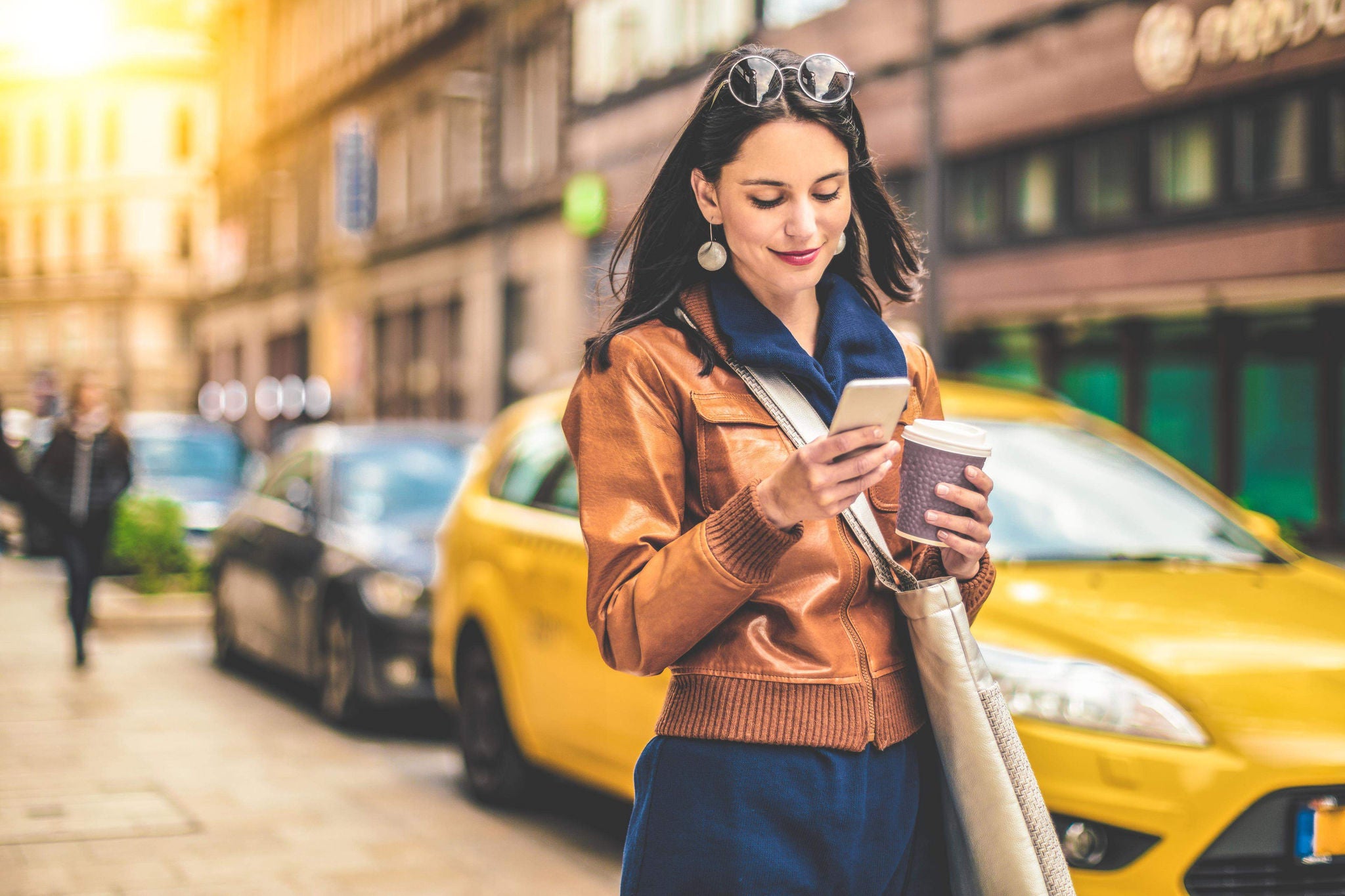 Woman looking at mobile while walking on the road