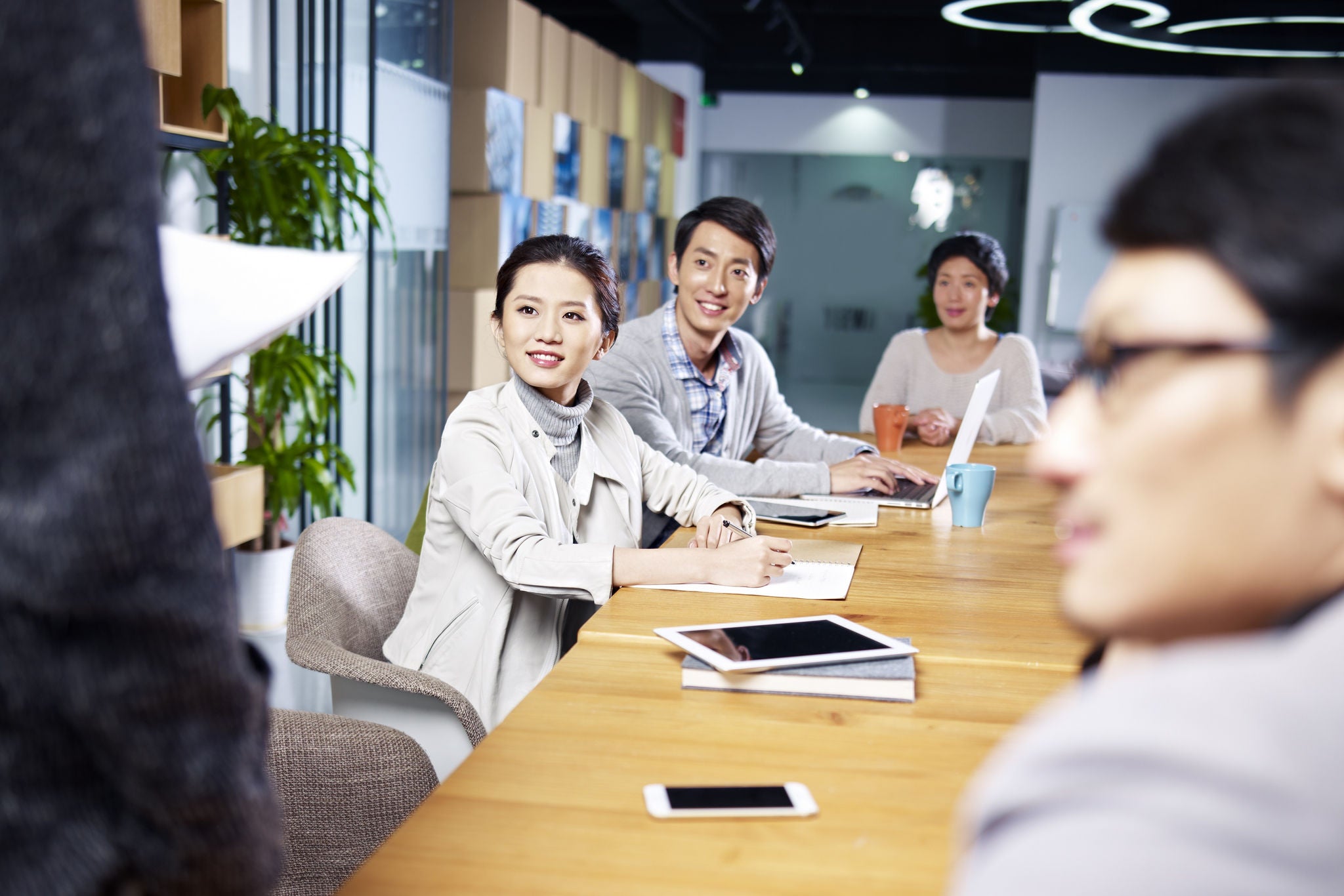 a team of young asian entrepreneurs meeting in office discussing ideas for new business.