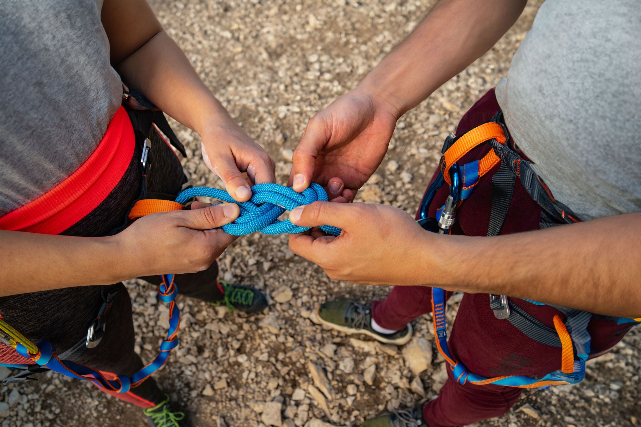 Hands of a couple of climbers making the eight knot in her harness