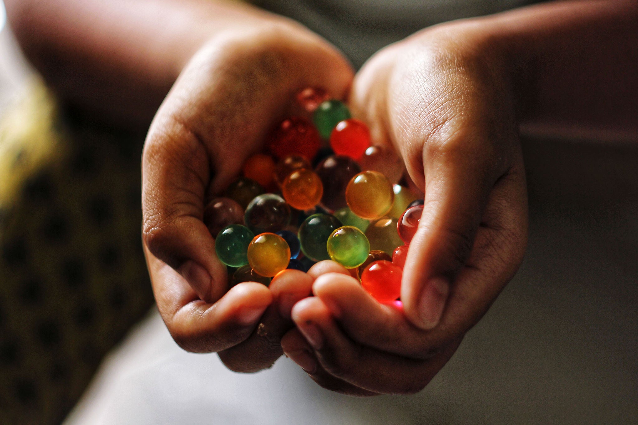 ey-cropped-hands-of-person-holding-colored-marbles