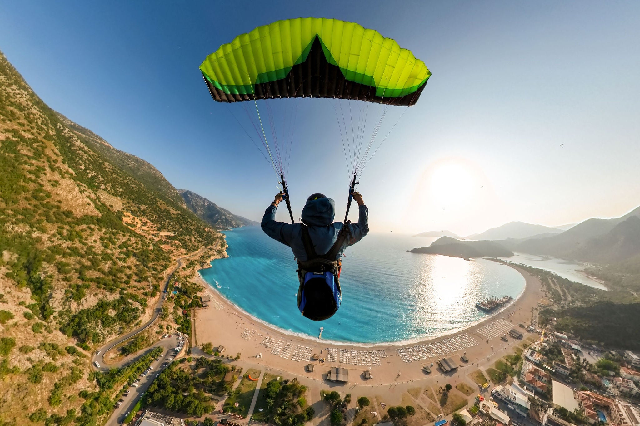 Golden moment of a paraglider pilot flying over the sea