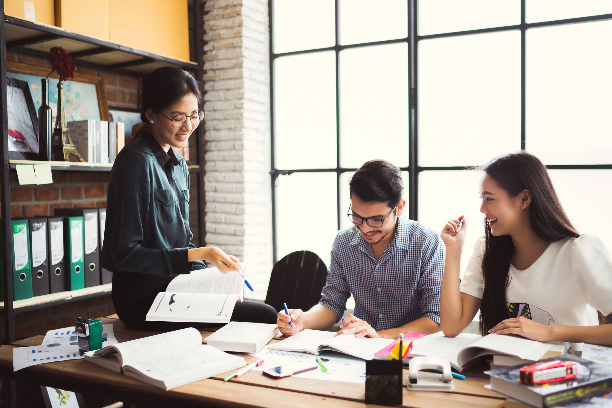 Three young professionals collaborate in a bright, modern workspace.