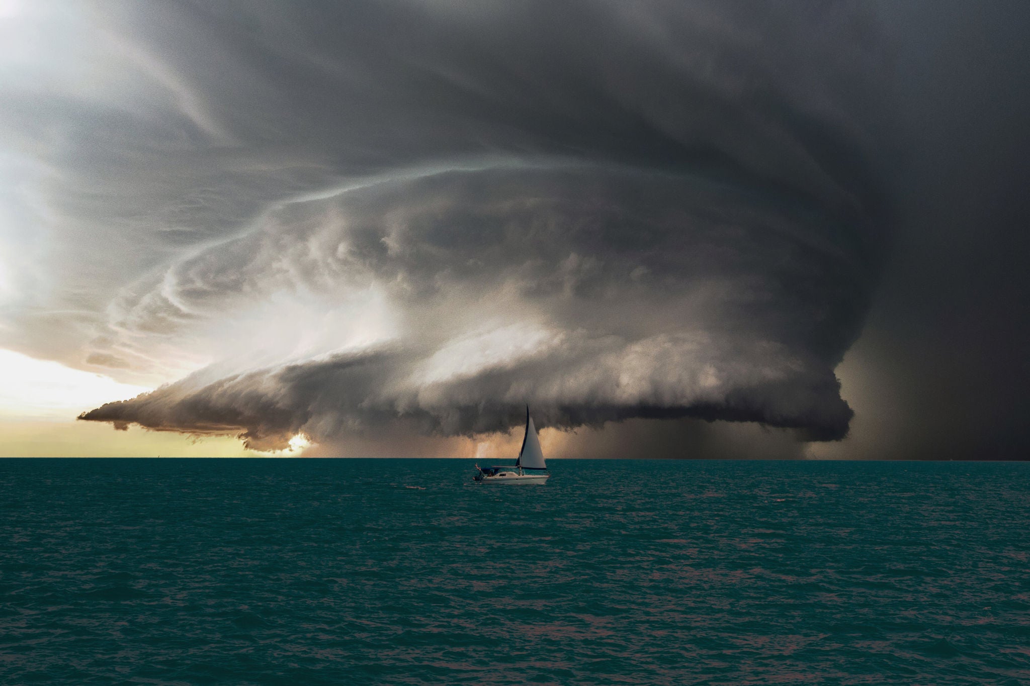 sailing boat on the open sea with storm clouds approaching