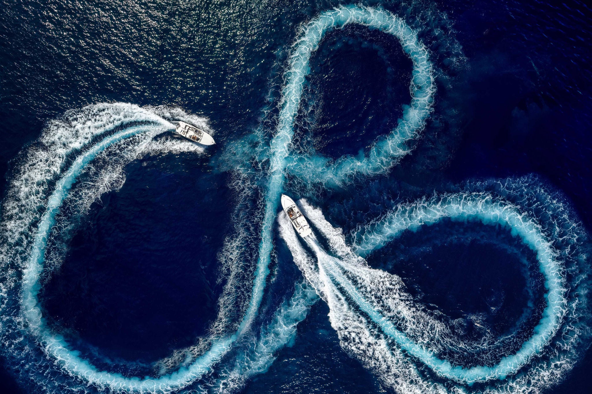 Aerial top view of a group of speed boats driving in circles