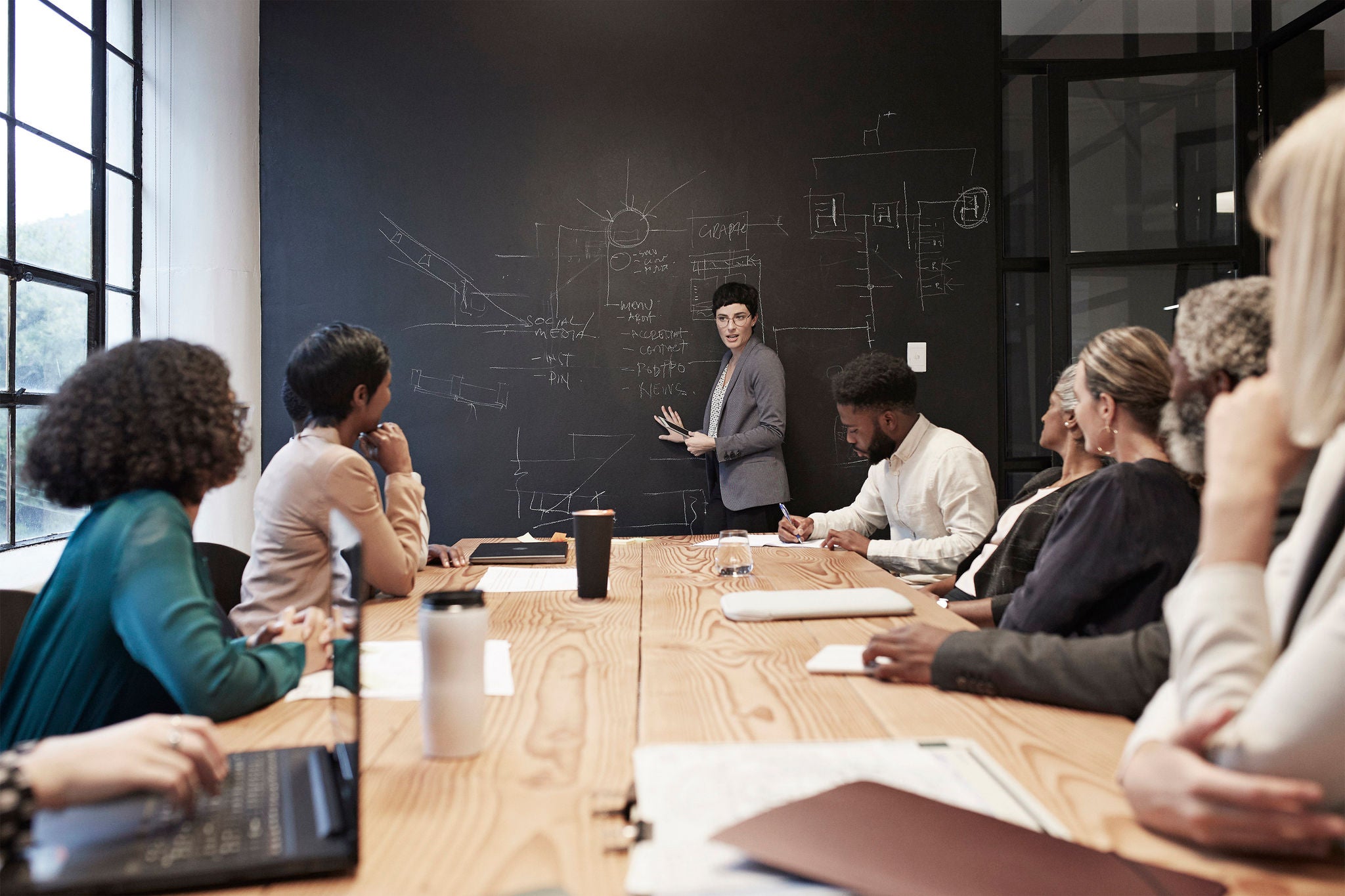 Entrepreneur explaining to female and male coworkers while standing in conference room during office meeting