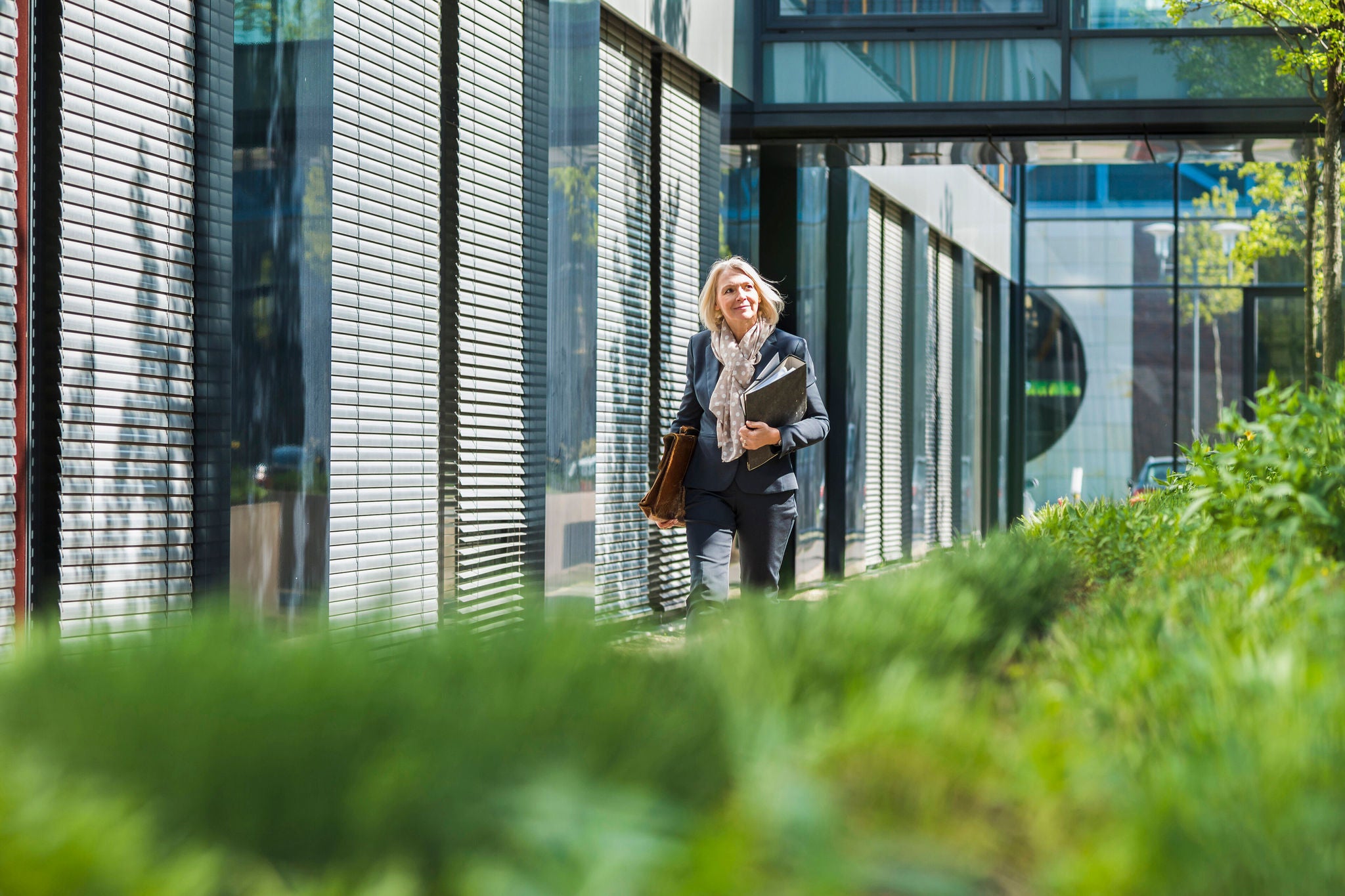 businesswoman carrying briefcase and files past office