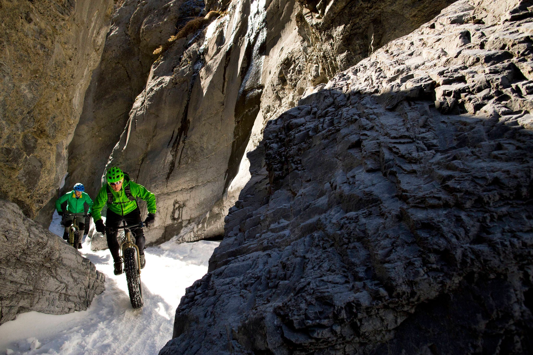 Two male cyclists enjoy a winter fat bike ride through a canyon