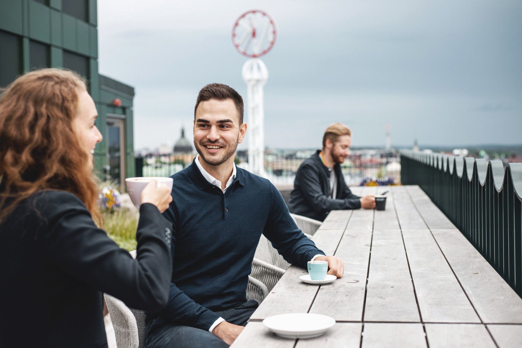 ey business women and man sitting on a balcony and having coffee