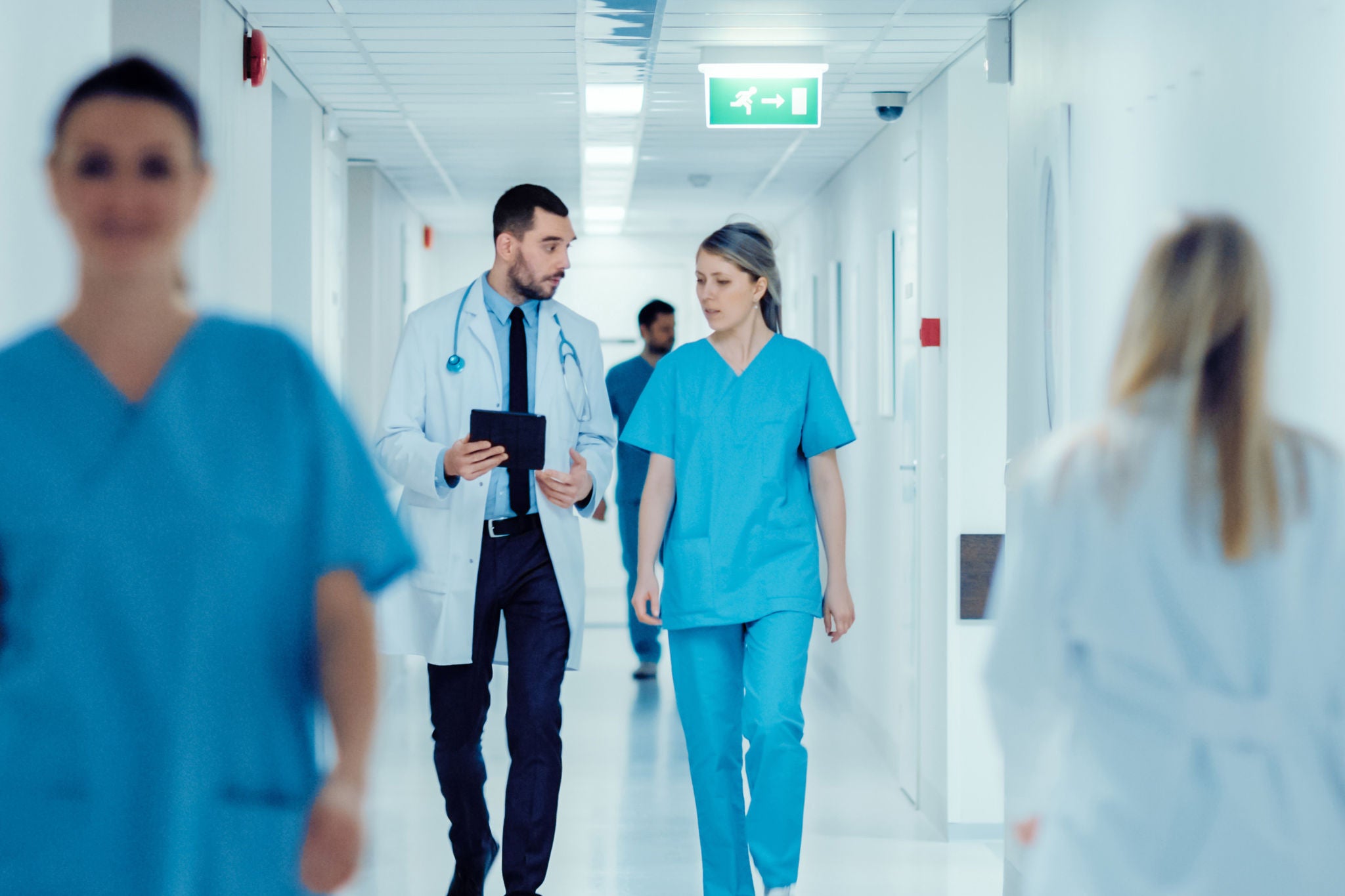 Surgeon and Female Doctor Walk Through Hospital Hallway