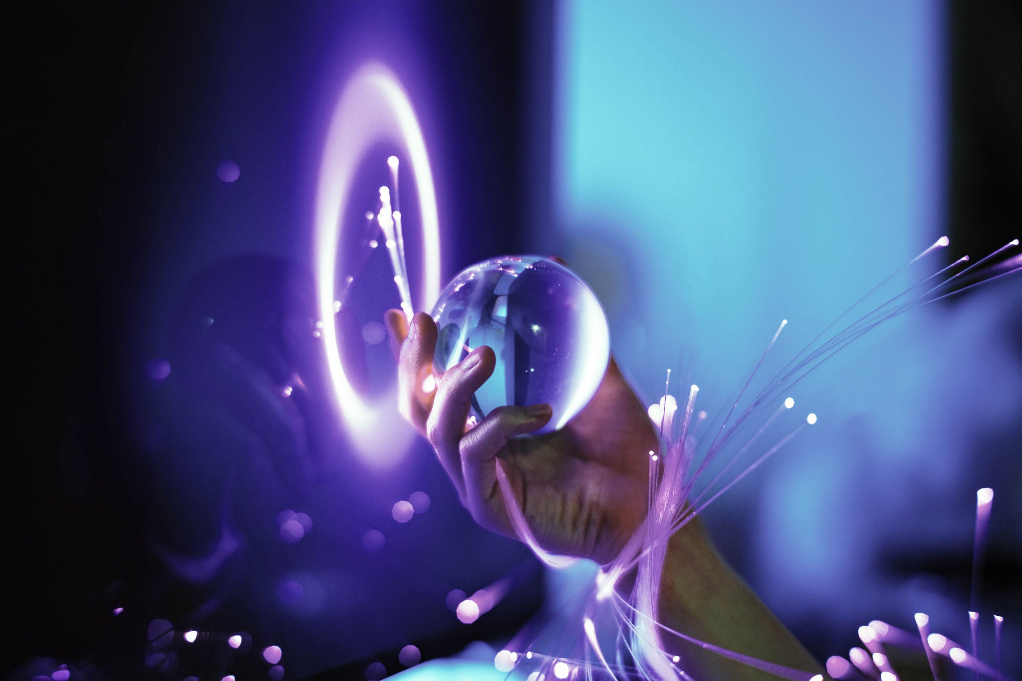 a close up of a hand wrapped in optical fibers and holding a crystal ball promo