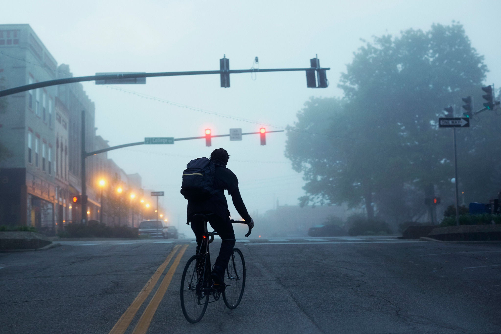 Silhouette Of Commuter Riding Bike During Misty Early Morning