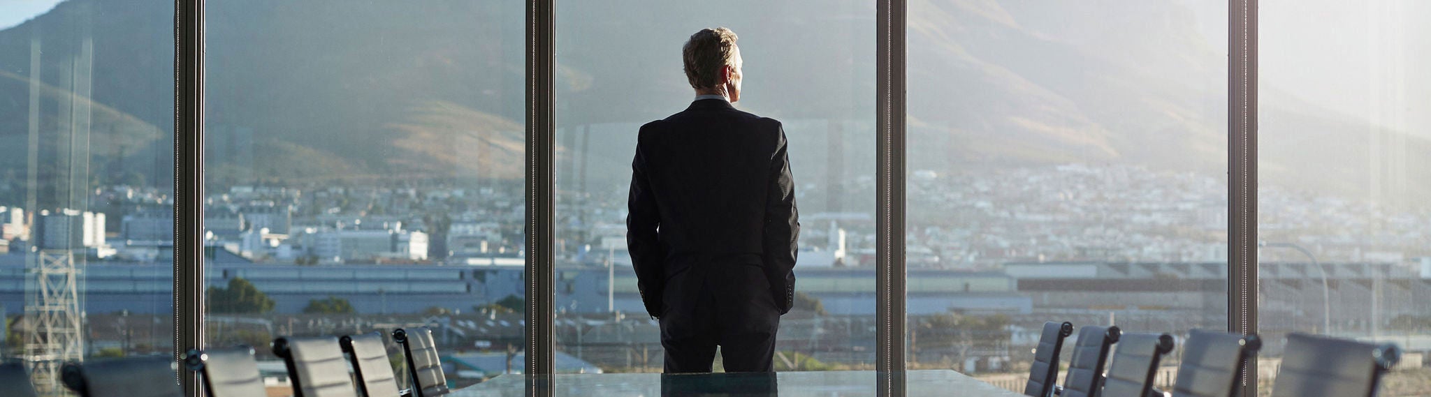 Man standing in office, looking outside through the glass