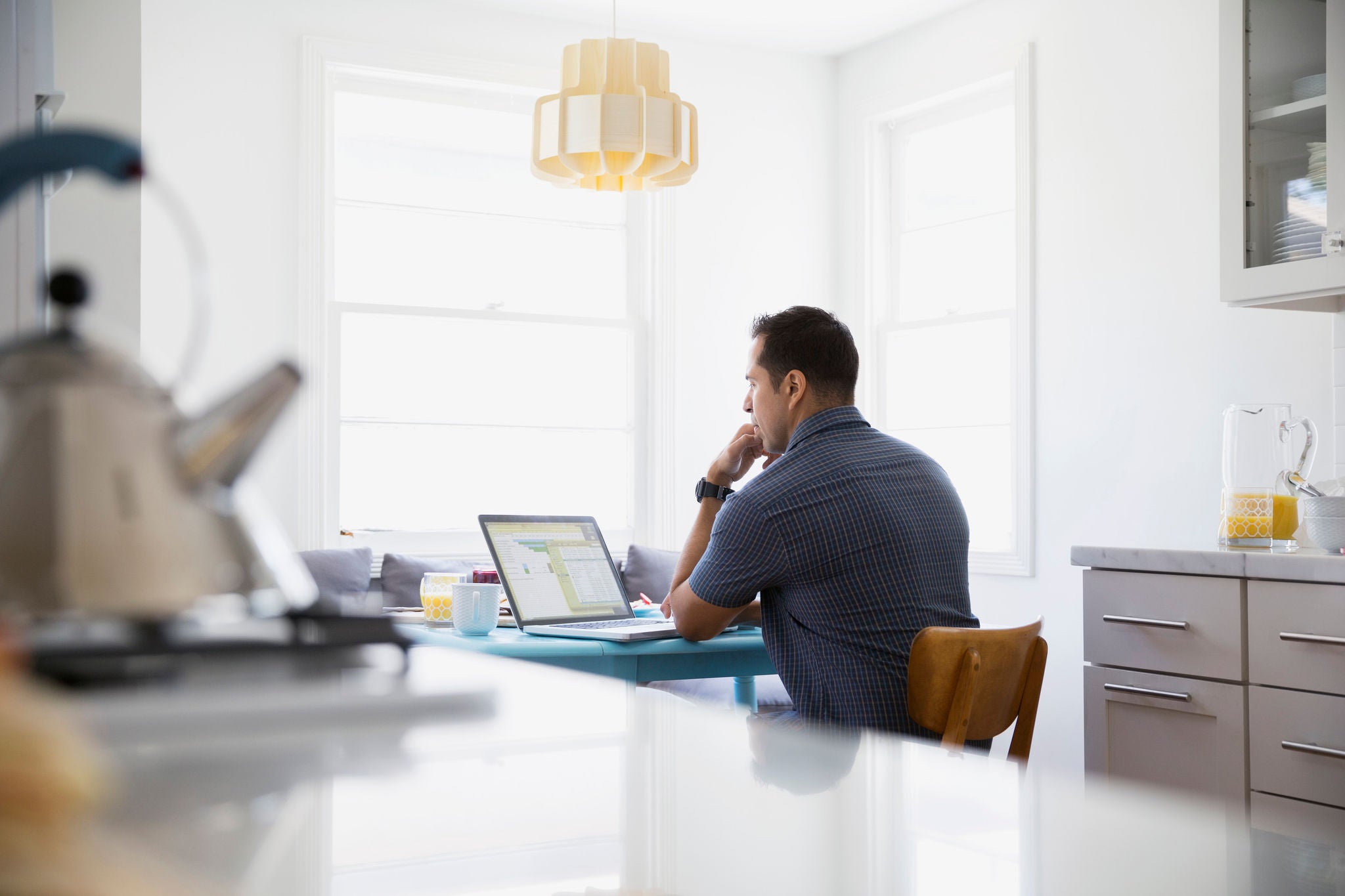 ey serious brunette man using laptop-at kitchen table