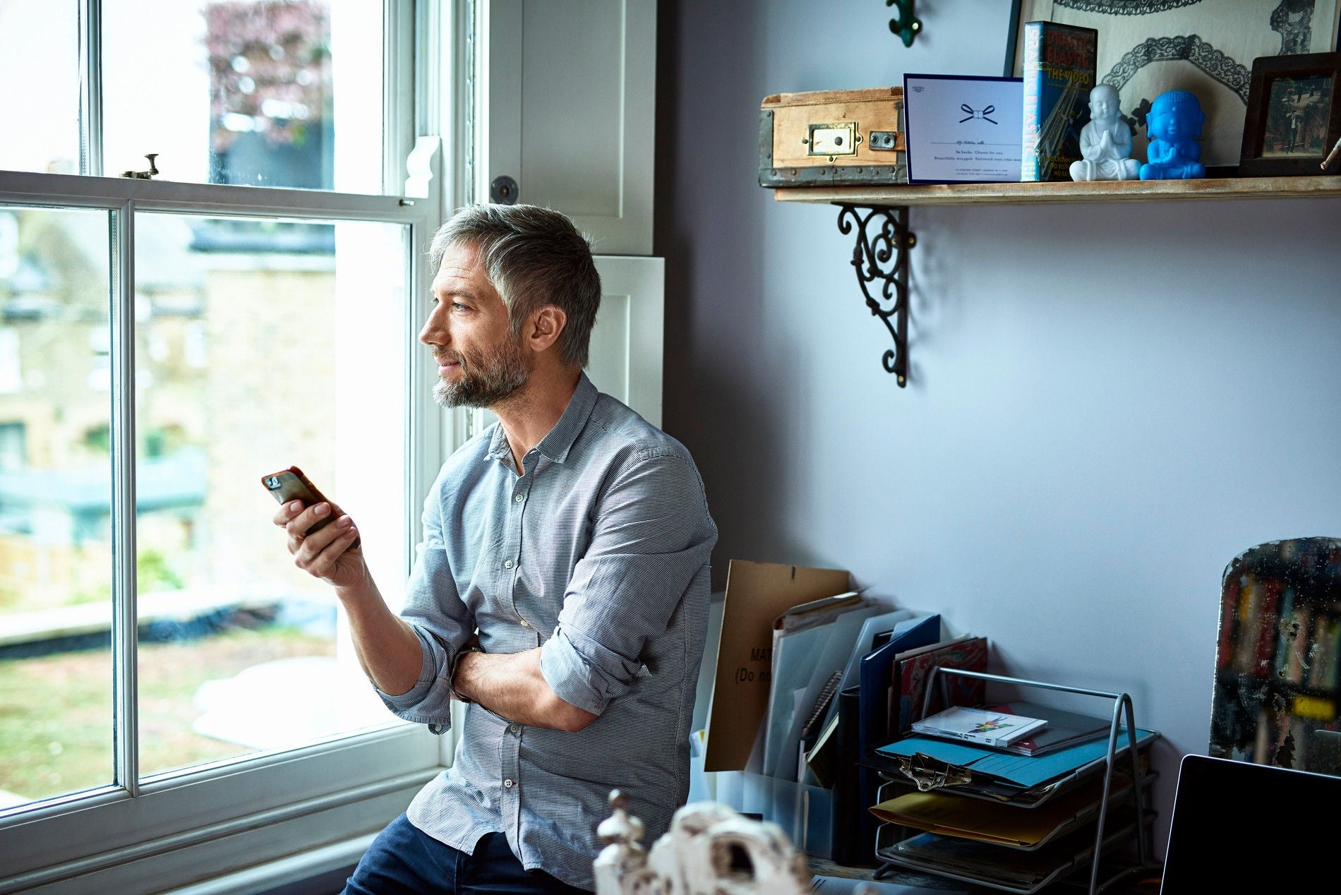 businessman using phone in home office looking through window