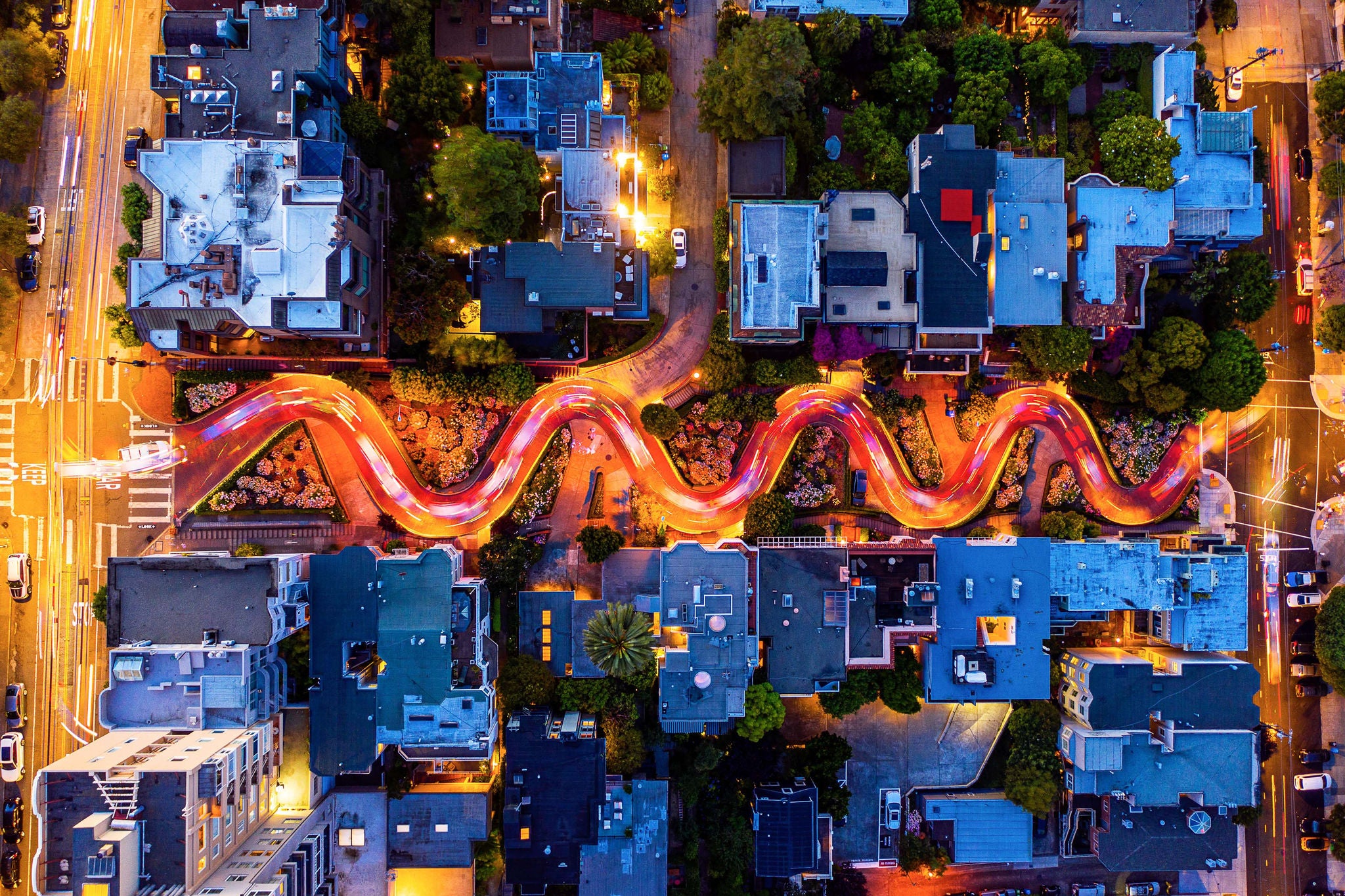 Ein horizontales Luftbild von Autos, die auf der beruehmten Lombard Street in San Francisco, Kalifornien, fahren. Einzelne Autolichter sind zu sehen.