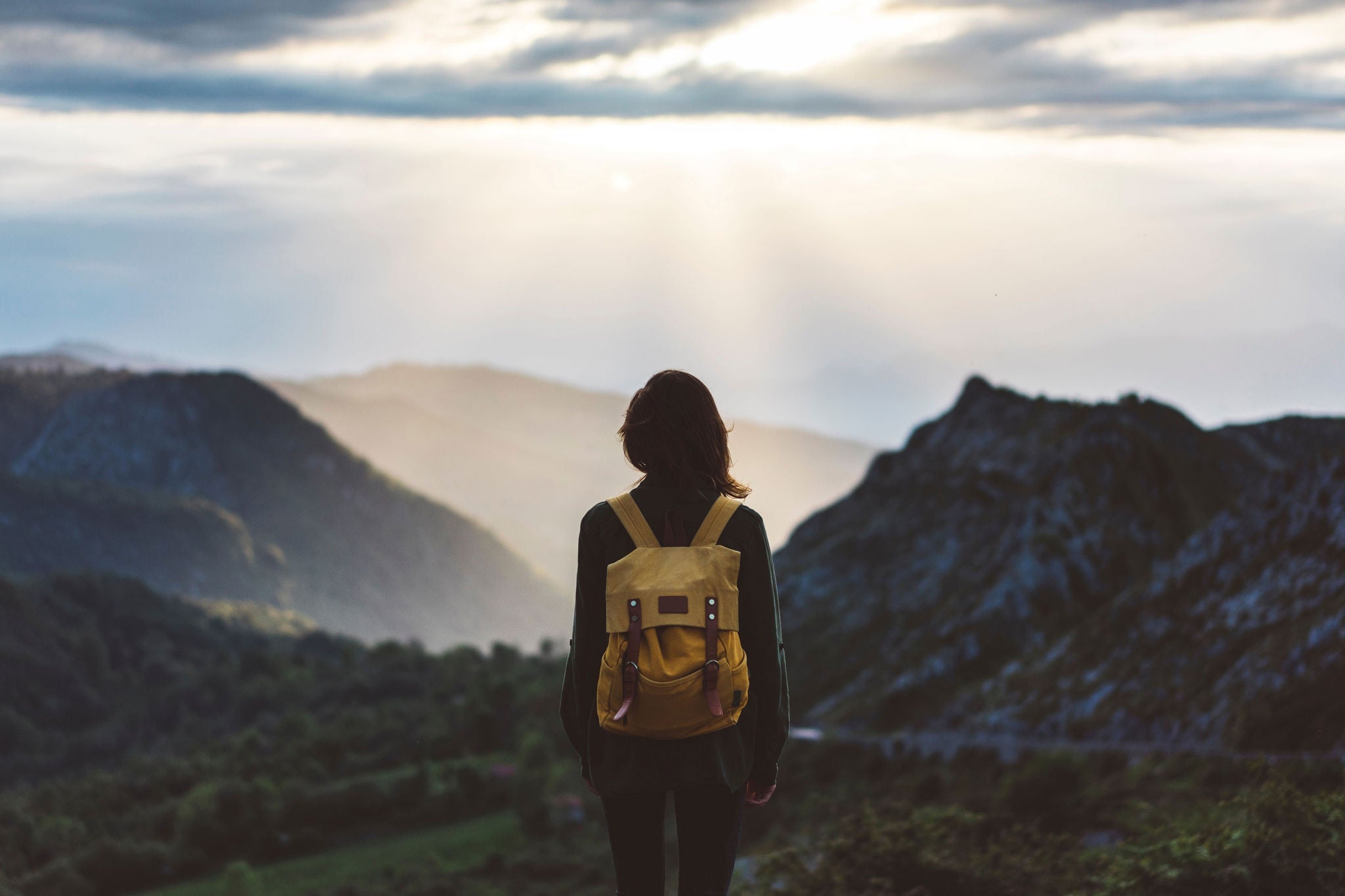 Woman standing with backpack viewing foggy mountain