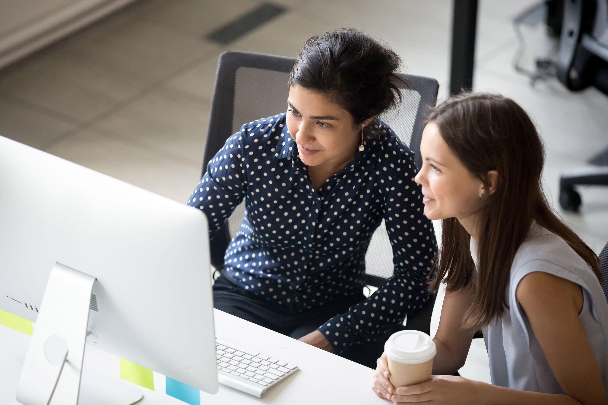 Multiracial colleagues sitting together looking at laptop screen in office