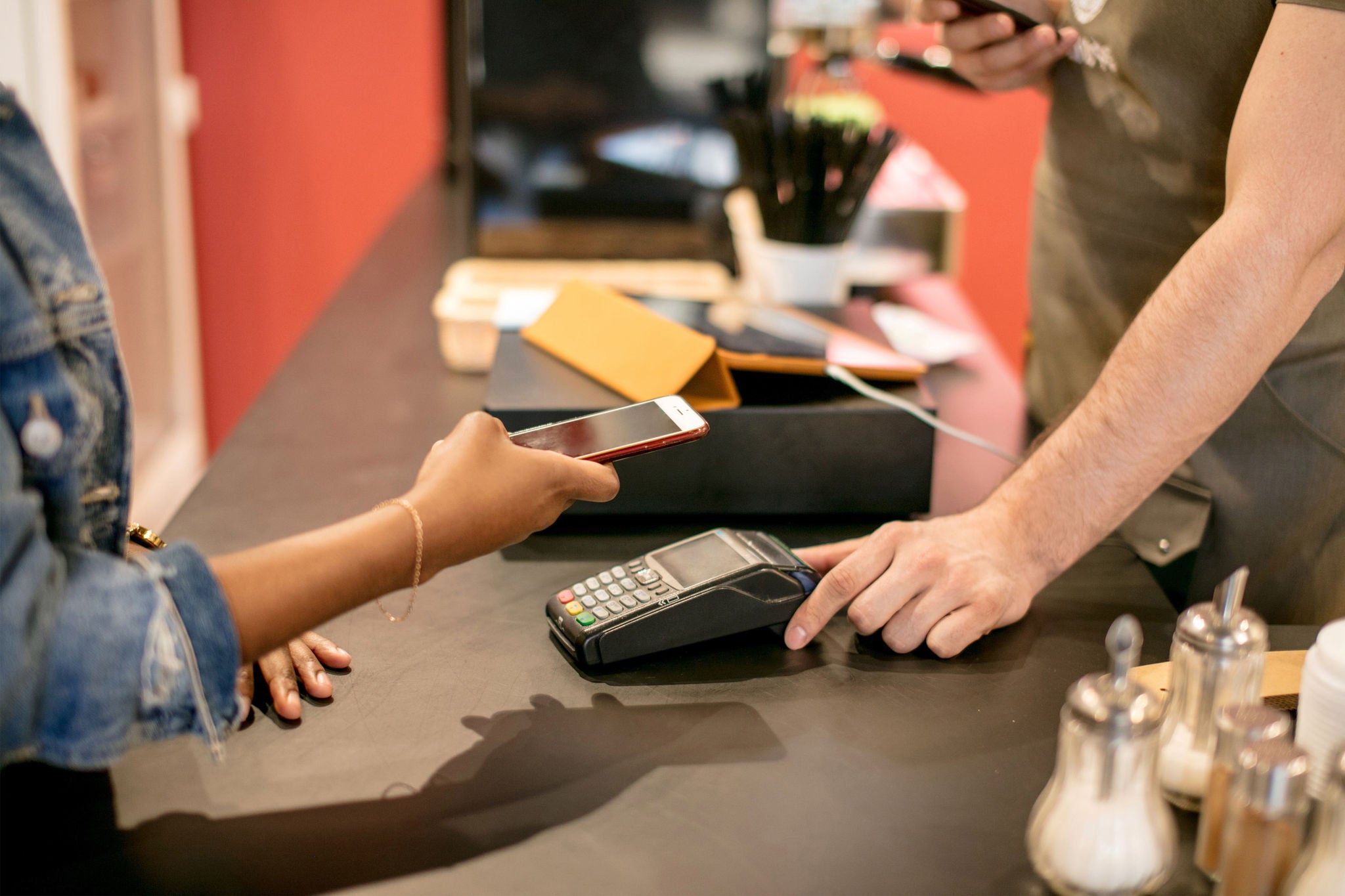 Mixed race woman using smartpay on her smart watch, to check out in restaurant, close up