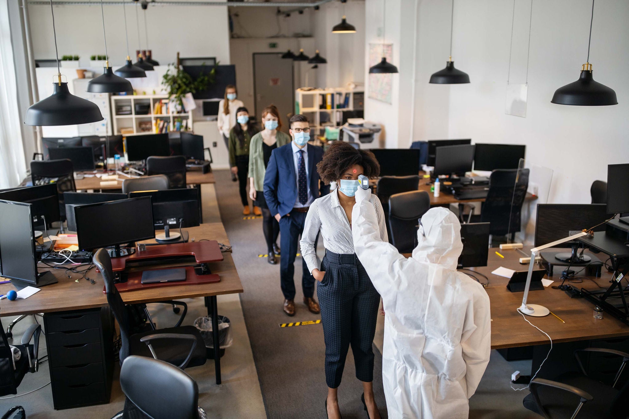 Worker checking the temperature of employees entering office background