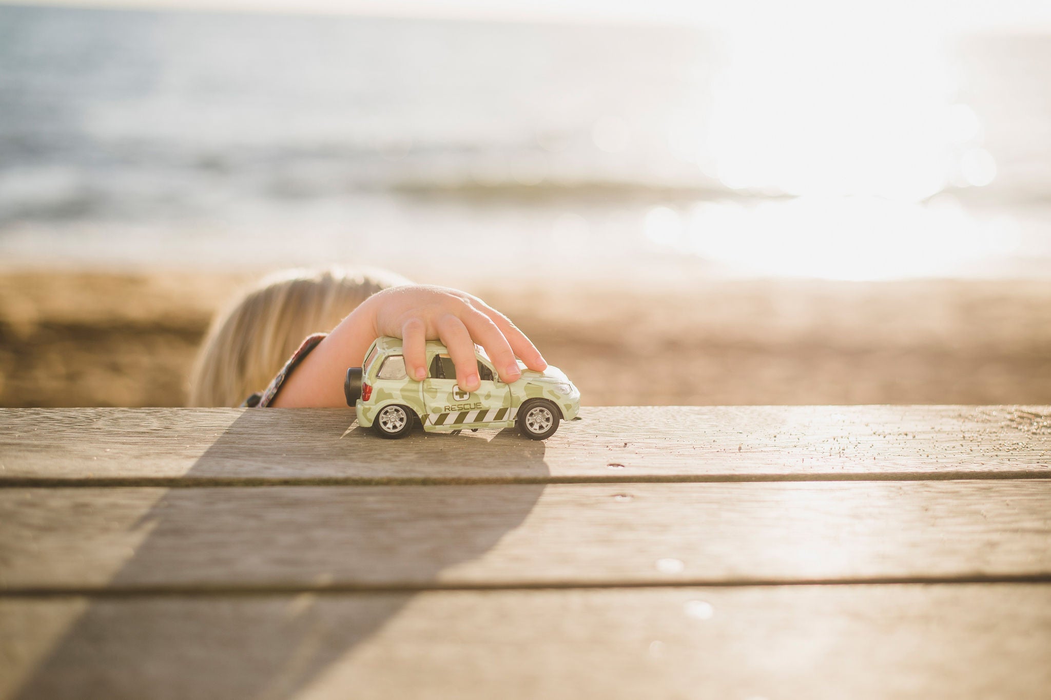 Jongen speelt met speelgoedauto op houten plank