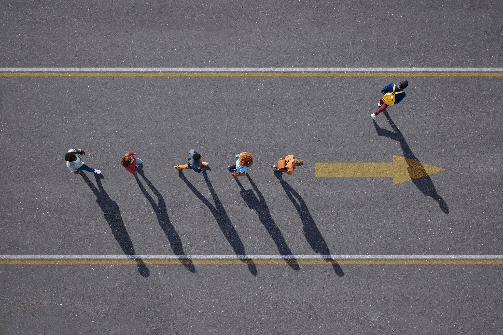 Aerial view of people walking in line on road with one person walking off