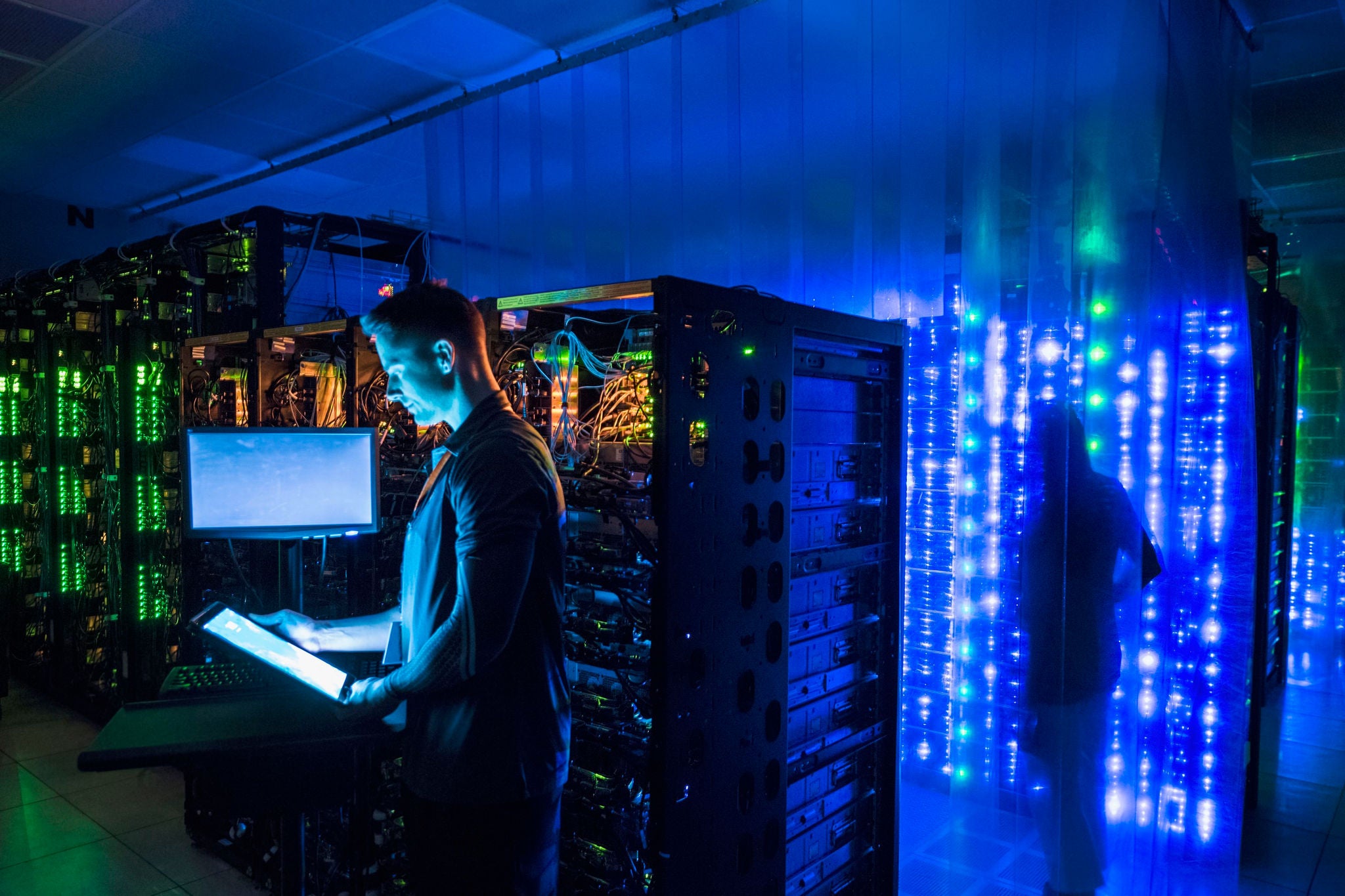 Man using digital tablet in dark server room