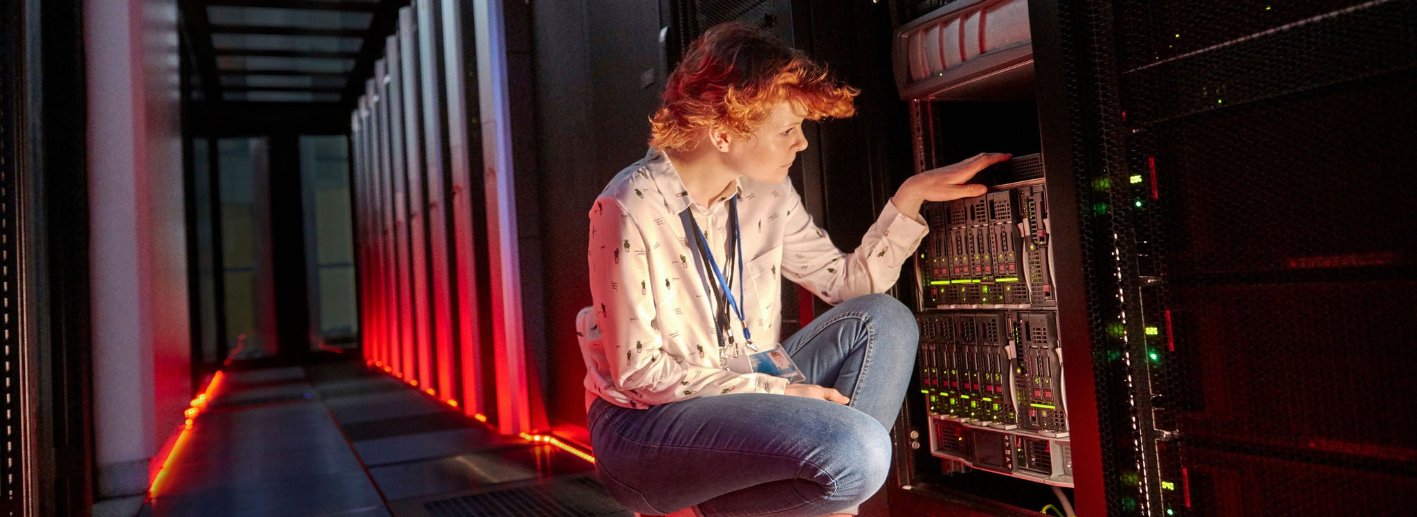 Female IT technician examining panel in dark server room