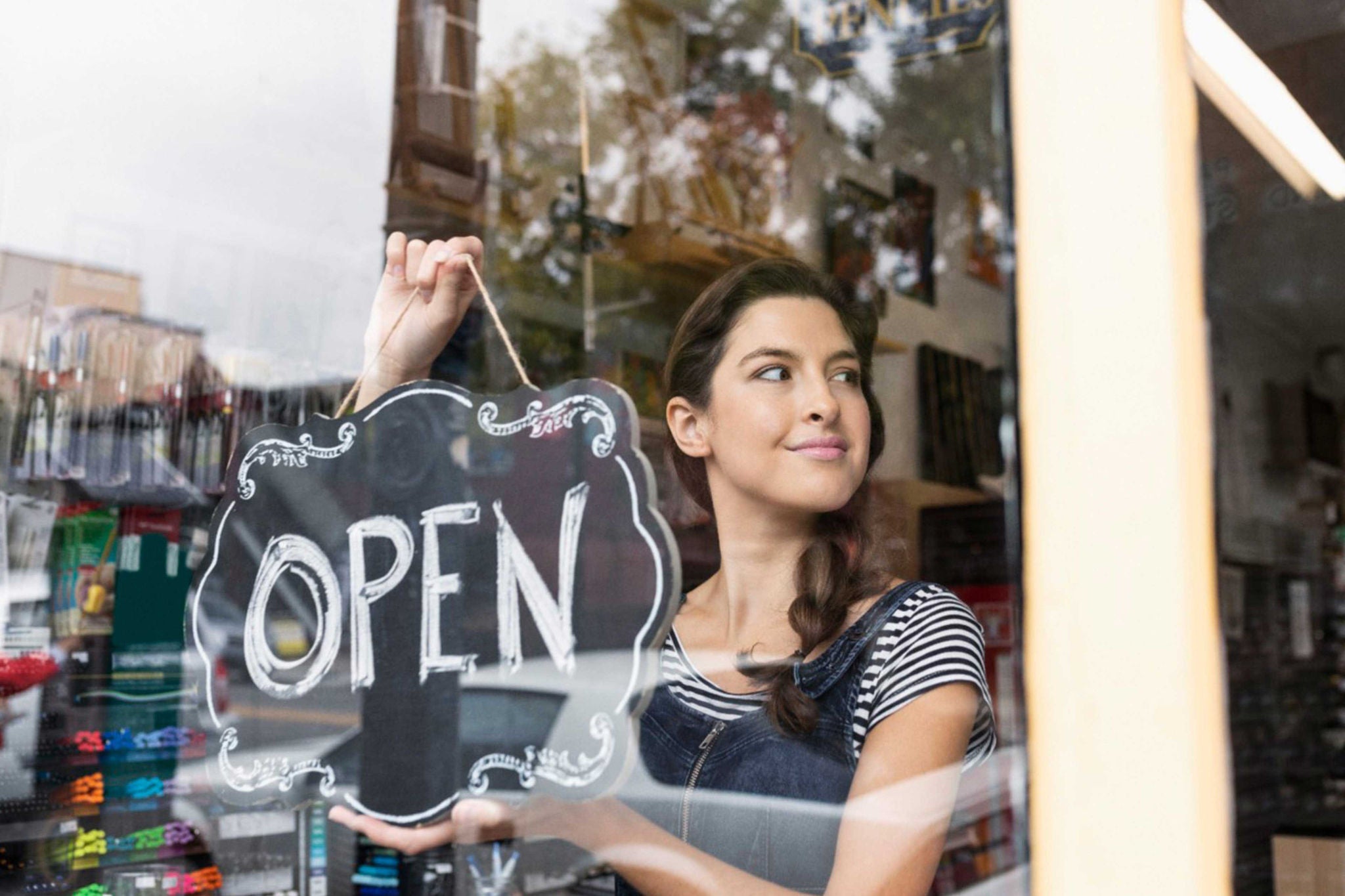 Woman holding an open sign in window