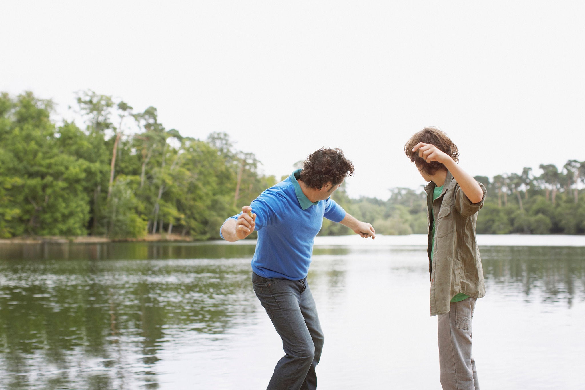 Father and son skimming stones in lake