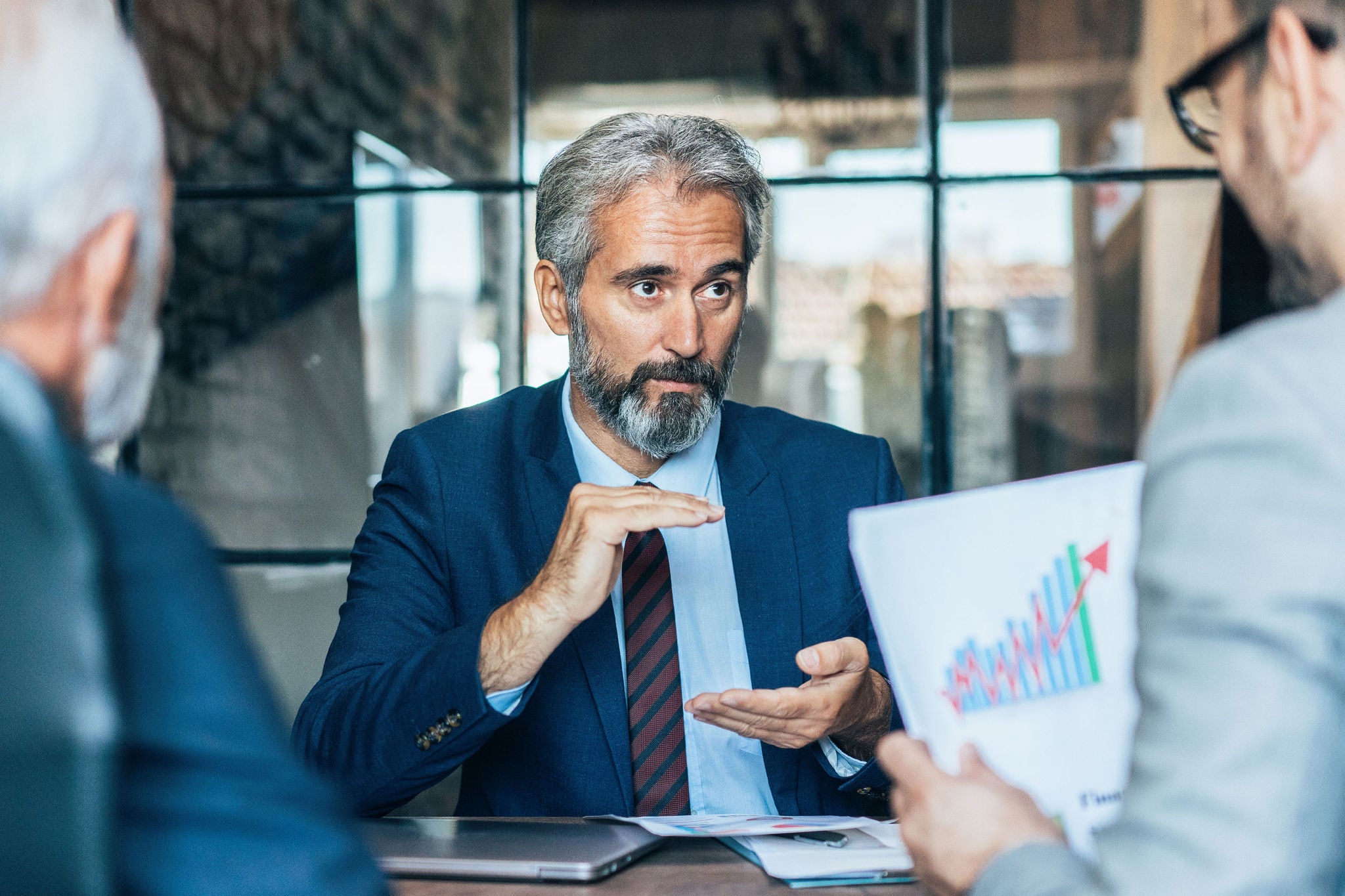 Three businessmen partners discussing financial report using graph and diagram on paperwork 