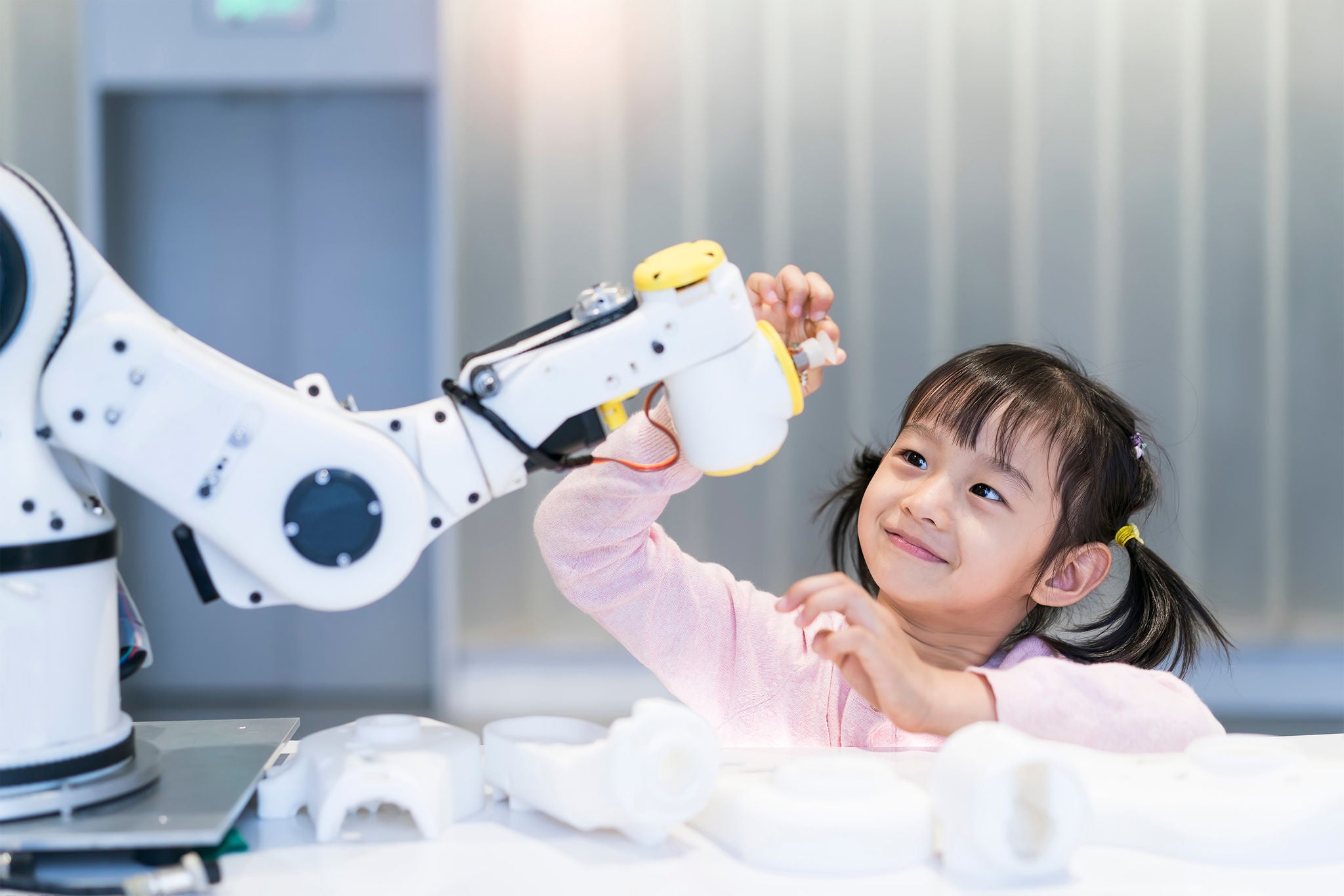 Asian little girl touching a robotic machine arm