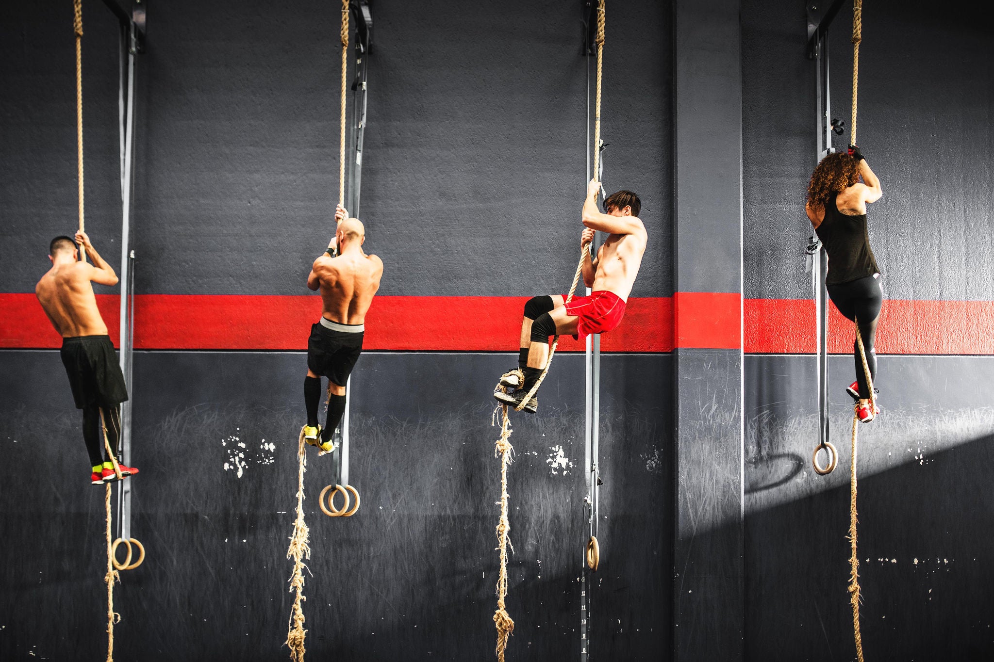 group of athletes climbing the rope in a gym