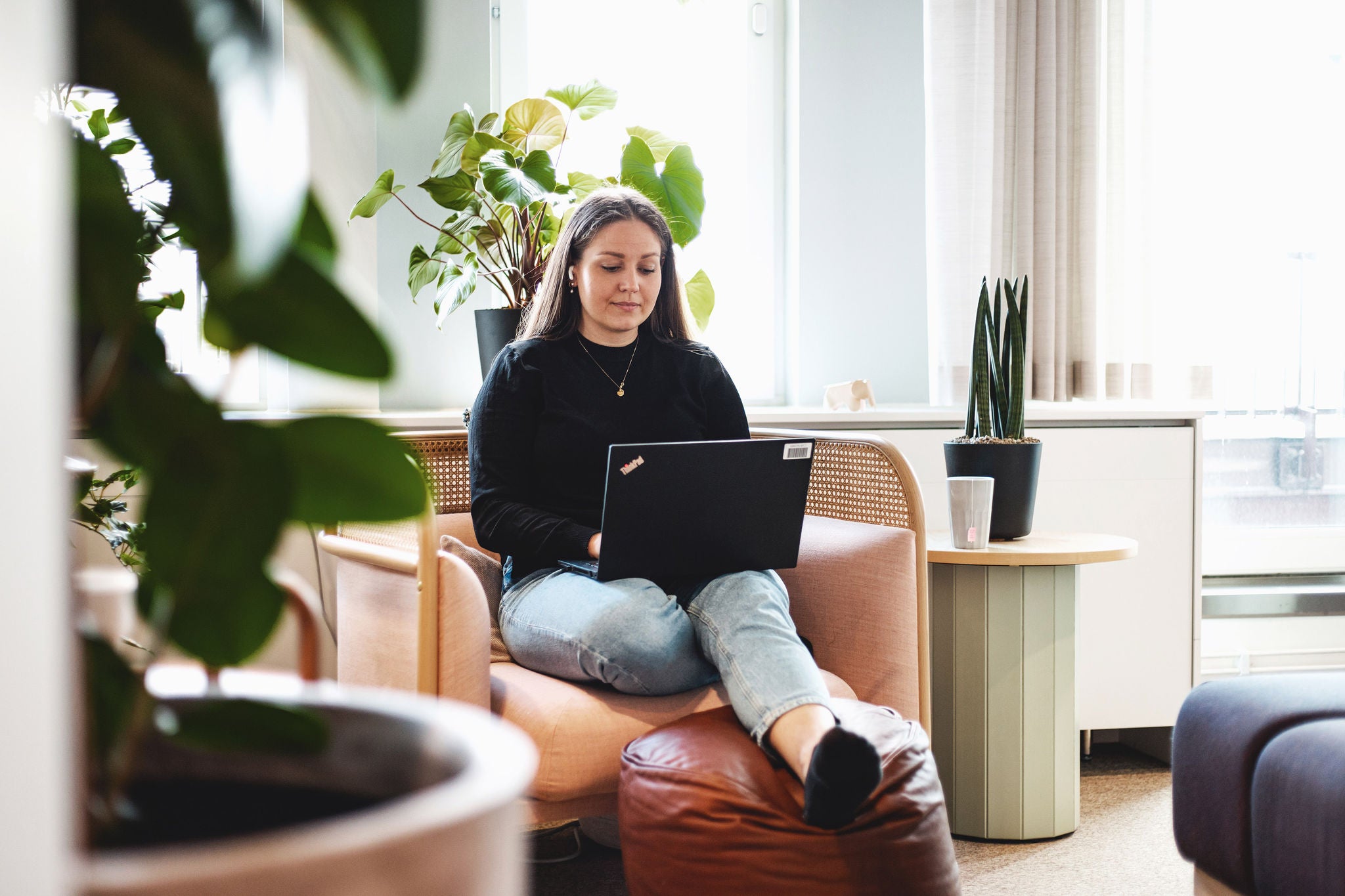 Ung kvinde sidder i stol og arbejder på pc