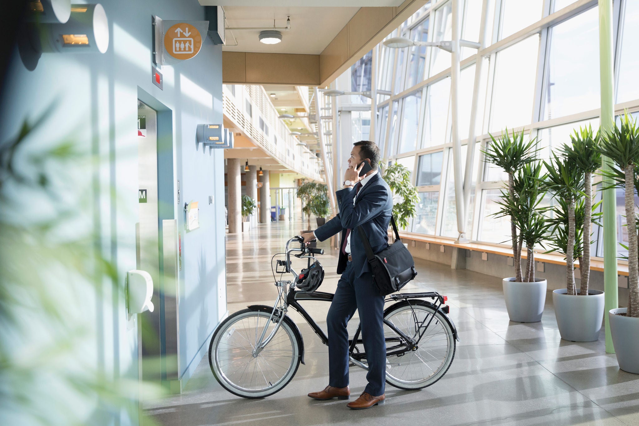 Zakenman met fiets tijdens het wachten in de lobby van het liftkantoor