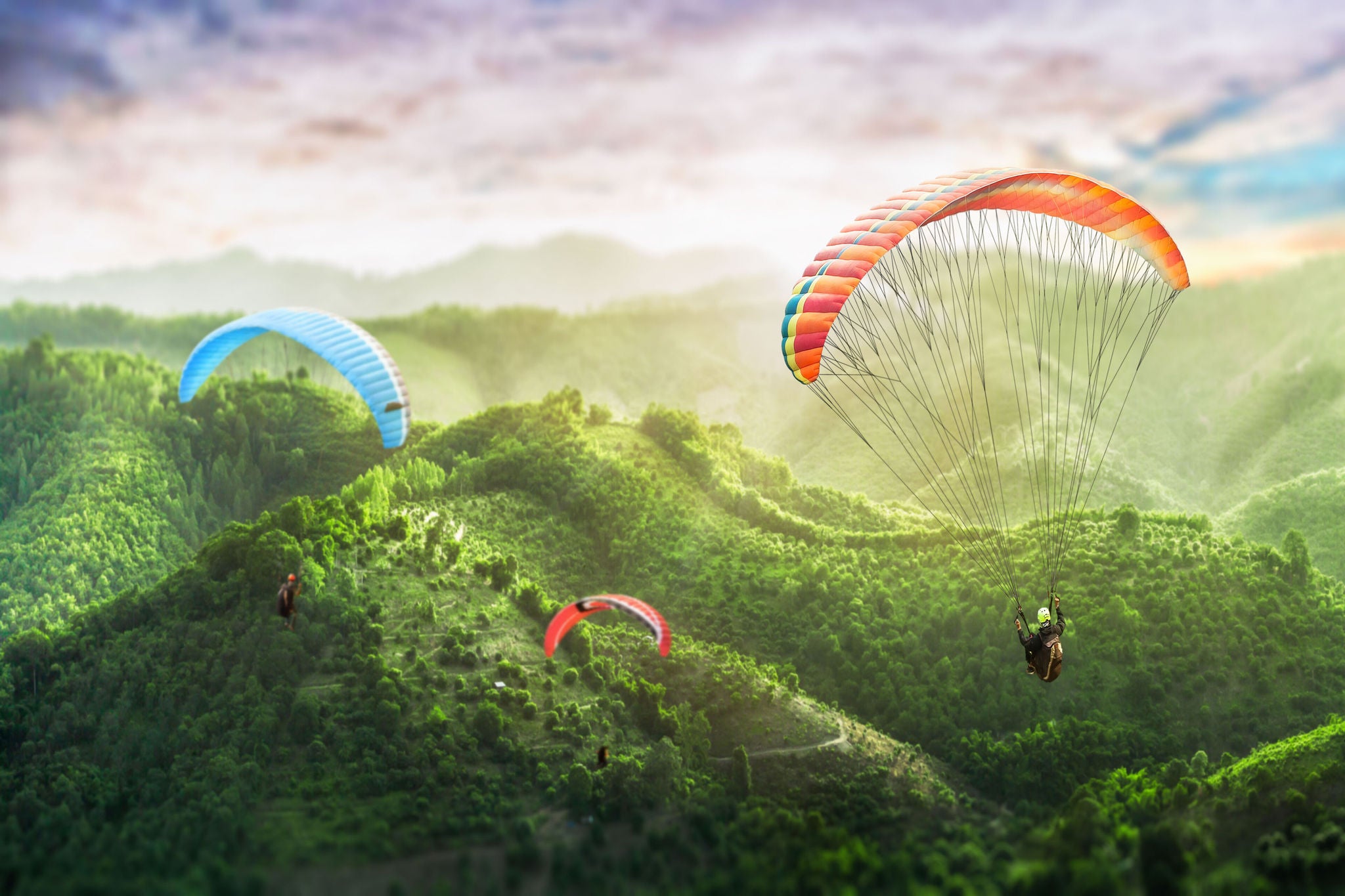 ey-three-people-fly-on-a-paraglider-against-the-backdrop-of-green-mountains.