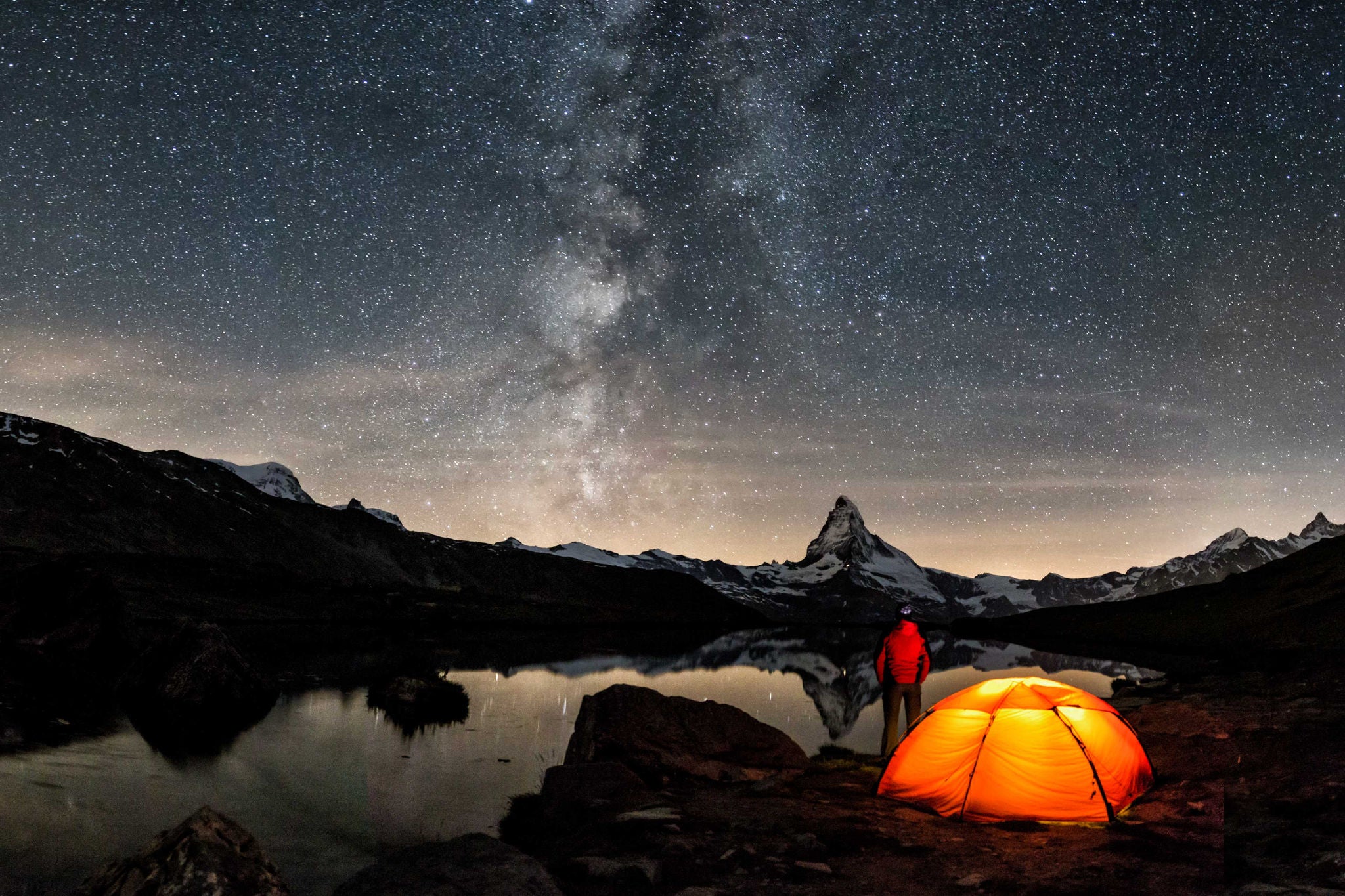 Hombre acampando en una noche estrellada en las montañas